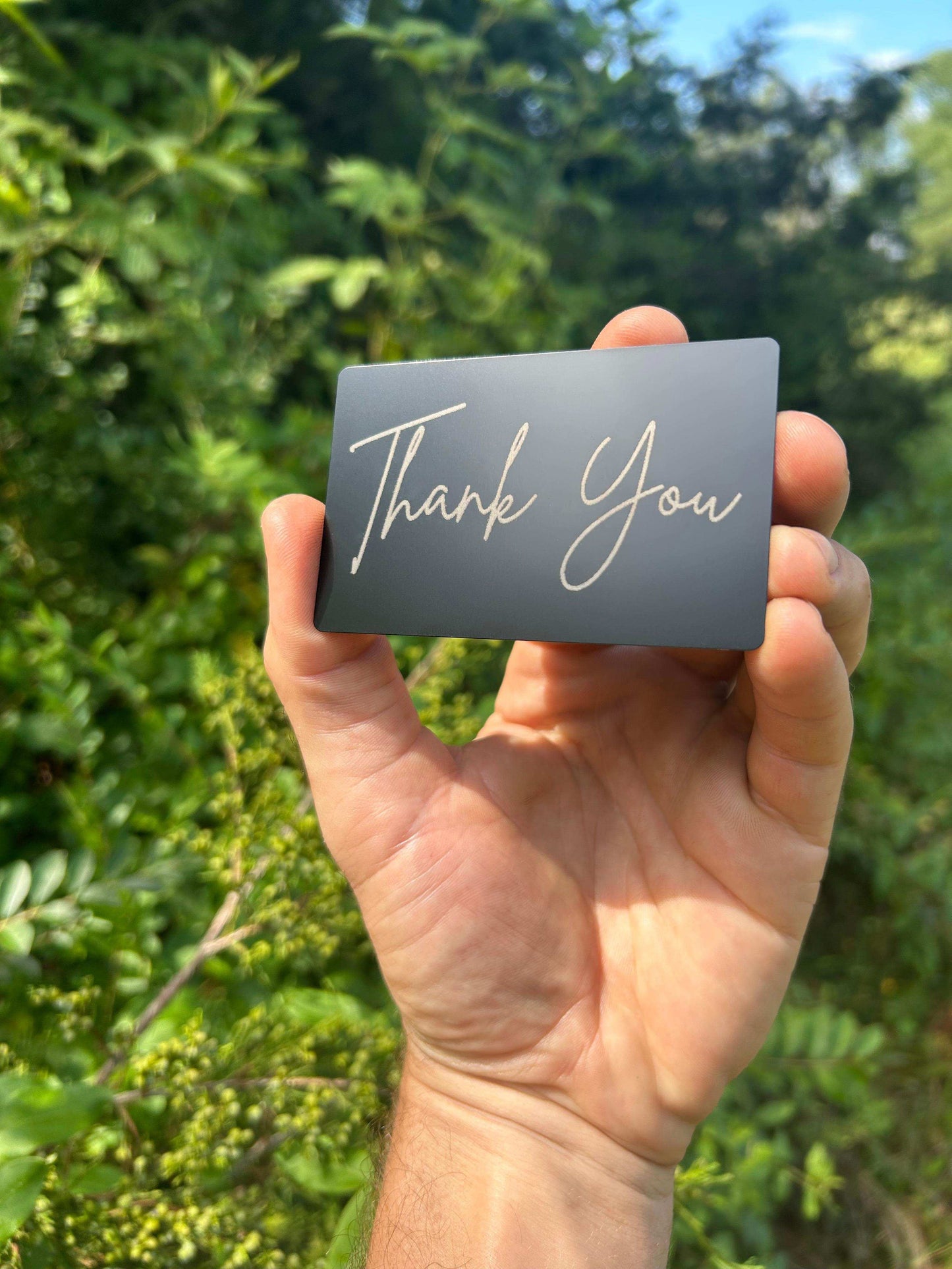 custom metal business card that has "thank you" engraved in silver on a matte black keepsake greeting card