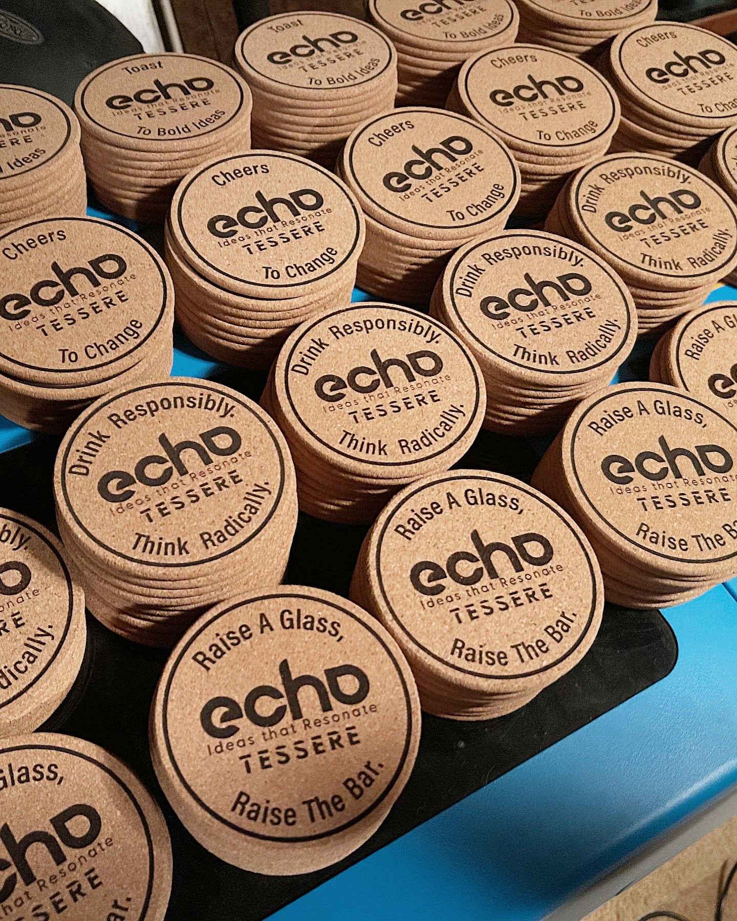 Stack of wooden coasters with 'echo' branding on a blue surface