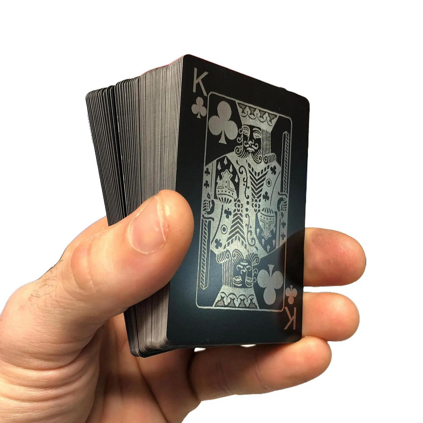 Hand holding a deck of metal playing cards with a King of Clubs card face up.