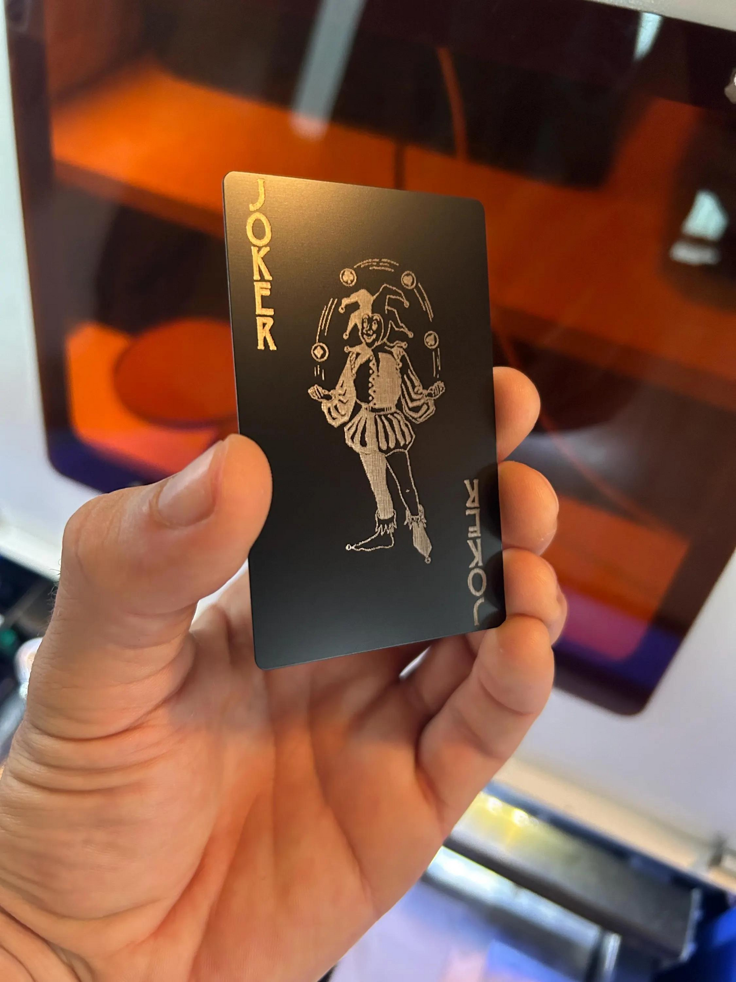 Hand holding a black card with white design and text against a blurred background