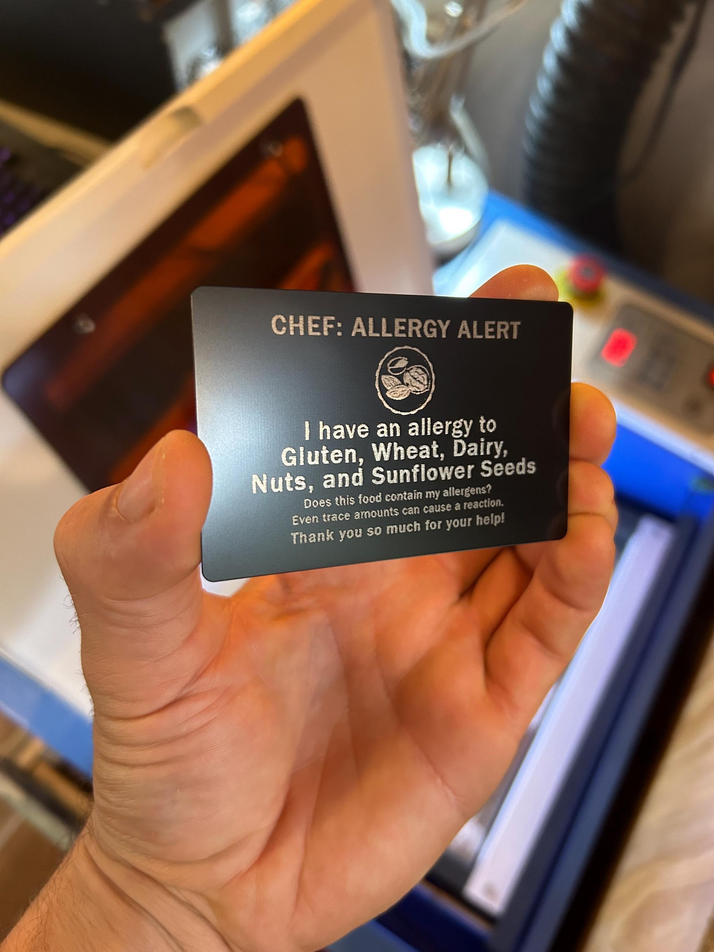 Hand holding a black allergy alert card with text