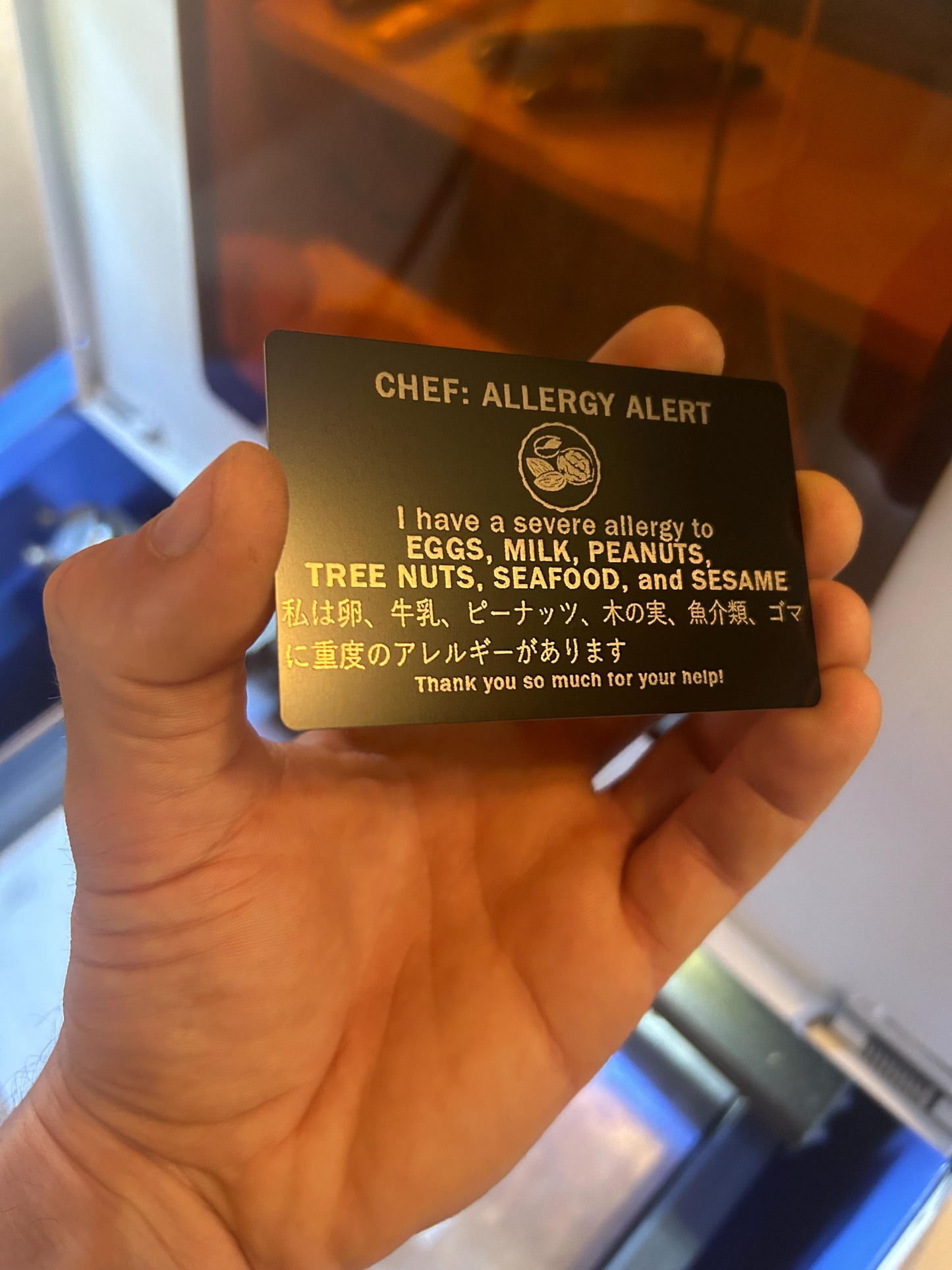 Hand holding a black allergy alert card with text