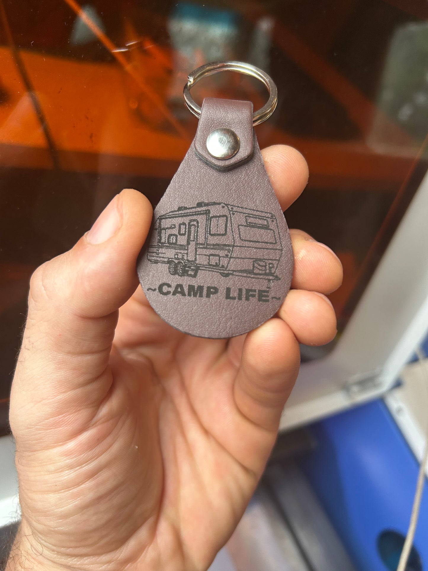Hand holding a brown leather keychain with a RV camper and the words 'CAMP LIFE' laser engraved