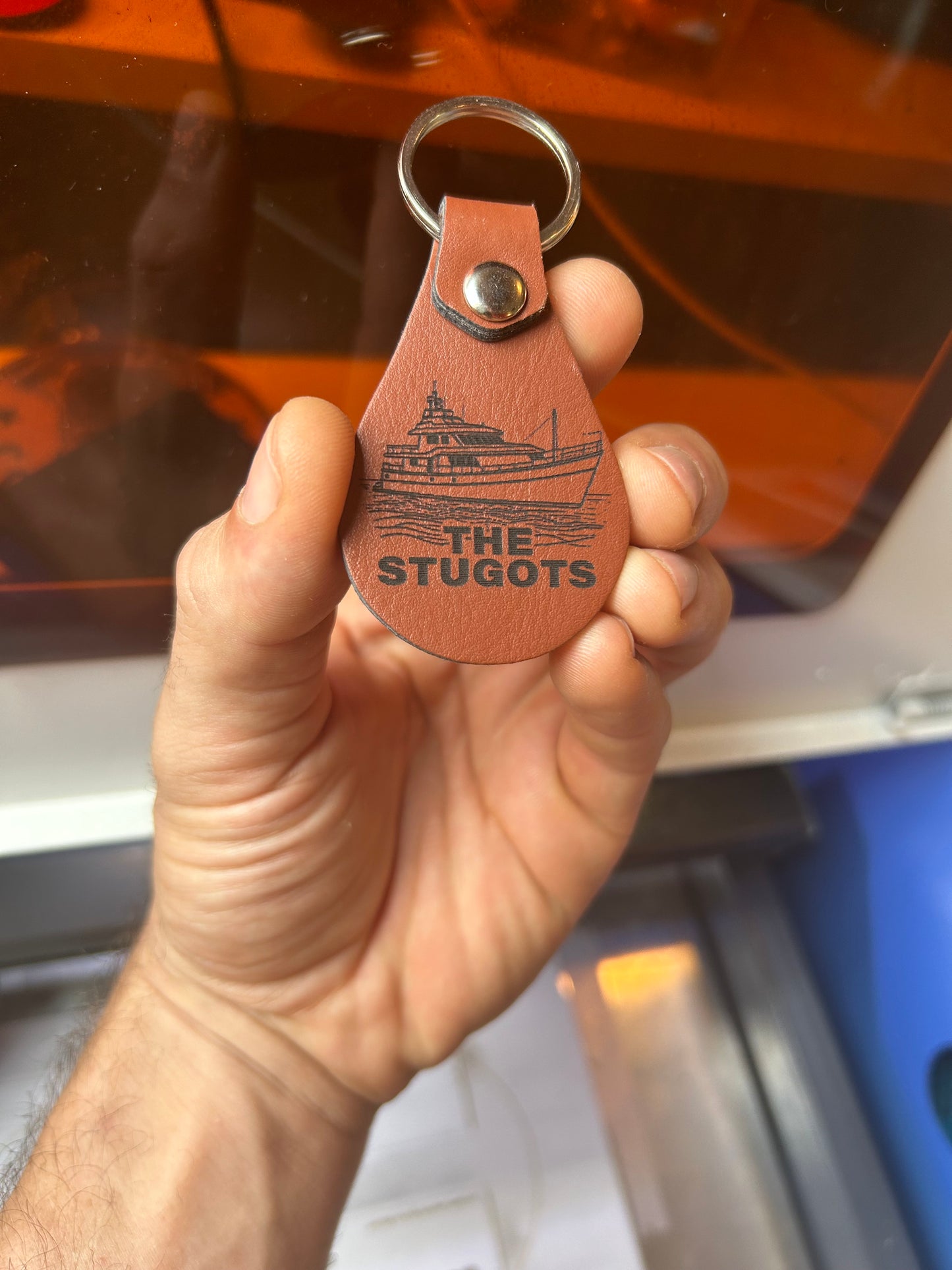 Hand holding a brown leather keychain with Yacht name and logo.