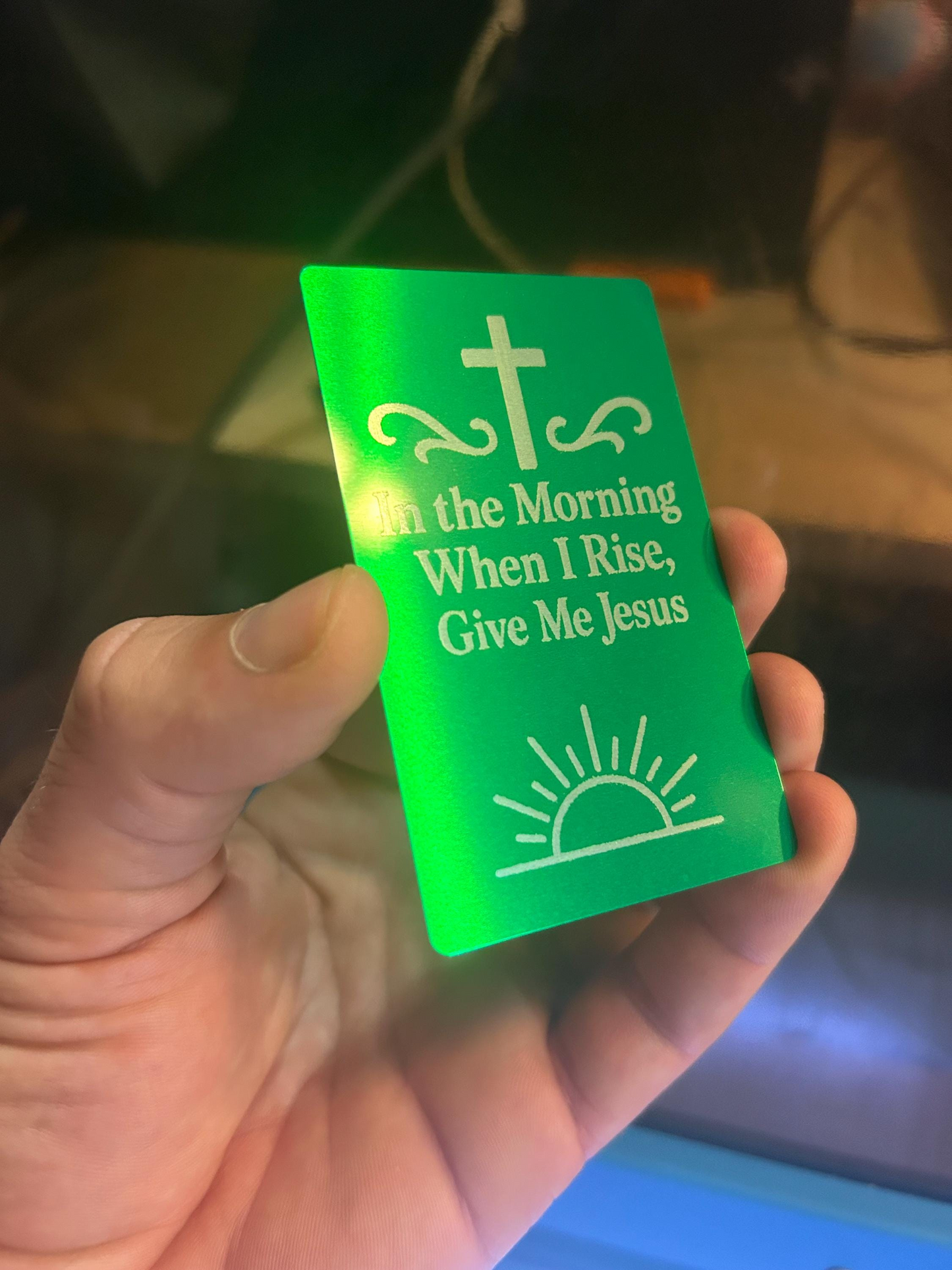 Side angle of hand displaying custom metal engraved card with quote “I Wanna Be Where The People Aren’t” – personalized keepsake with cross and sunrise imagery