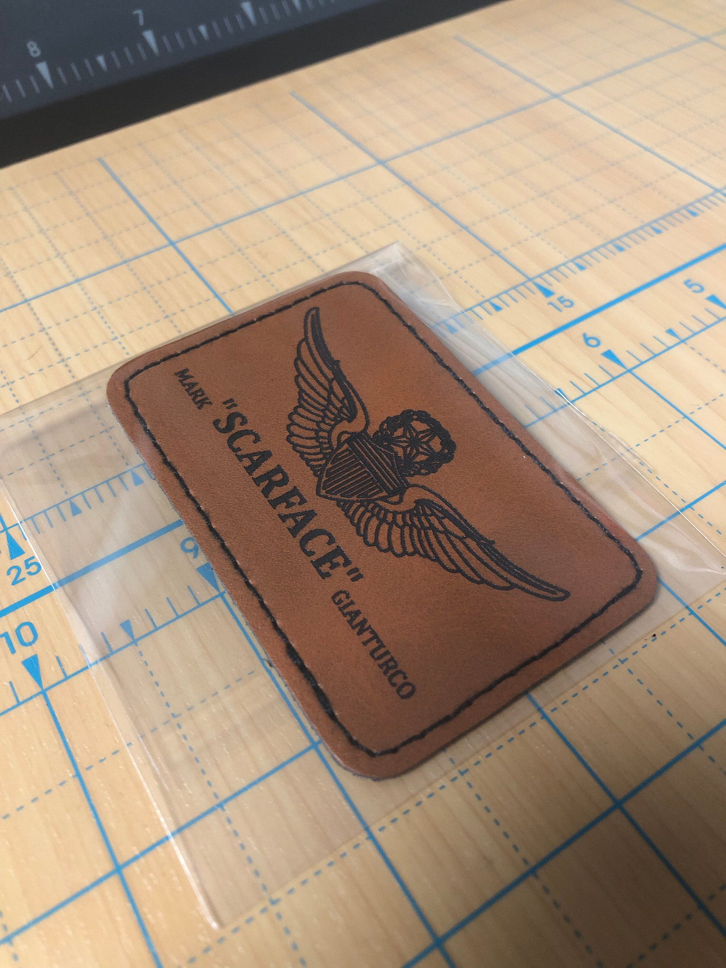 Brown leather patch with nickname, name and flight wings logo on a grid surface