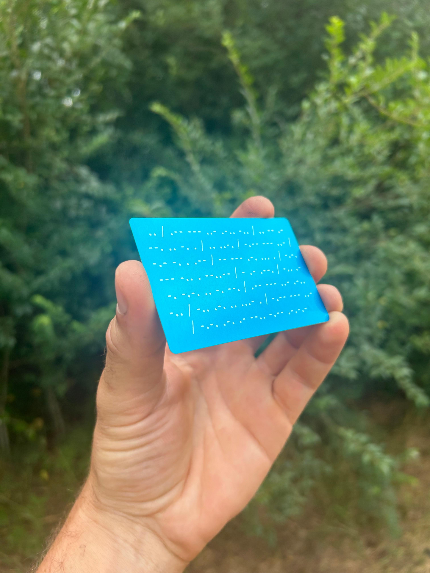 Hand holding a blue card with text against a blurred green background
