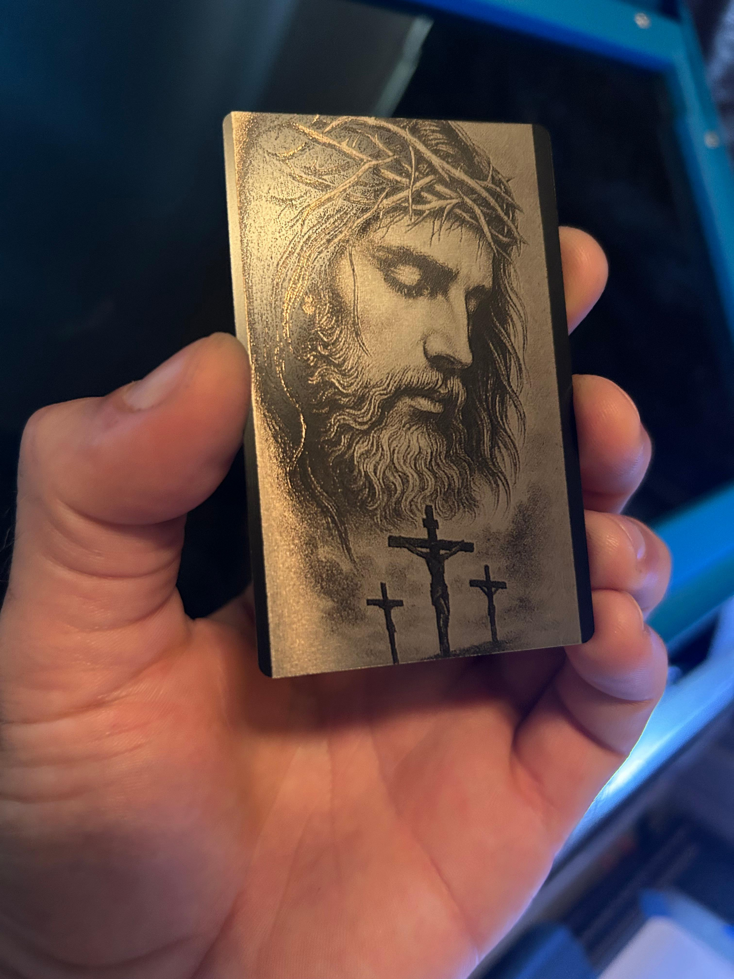 hand holding faith inspired metal laser engraved bible bookmark, with depiction of jesus on the cross