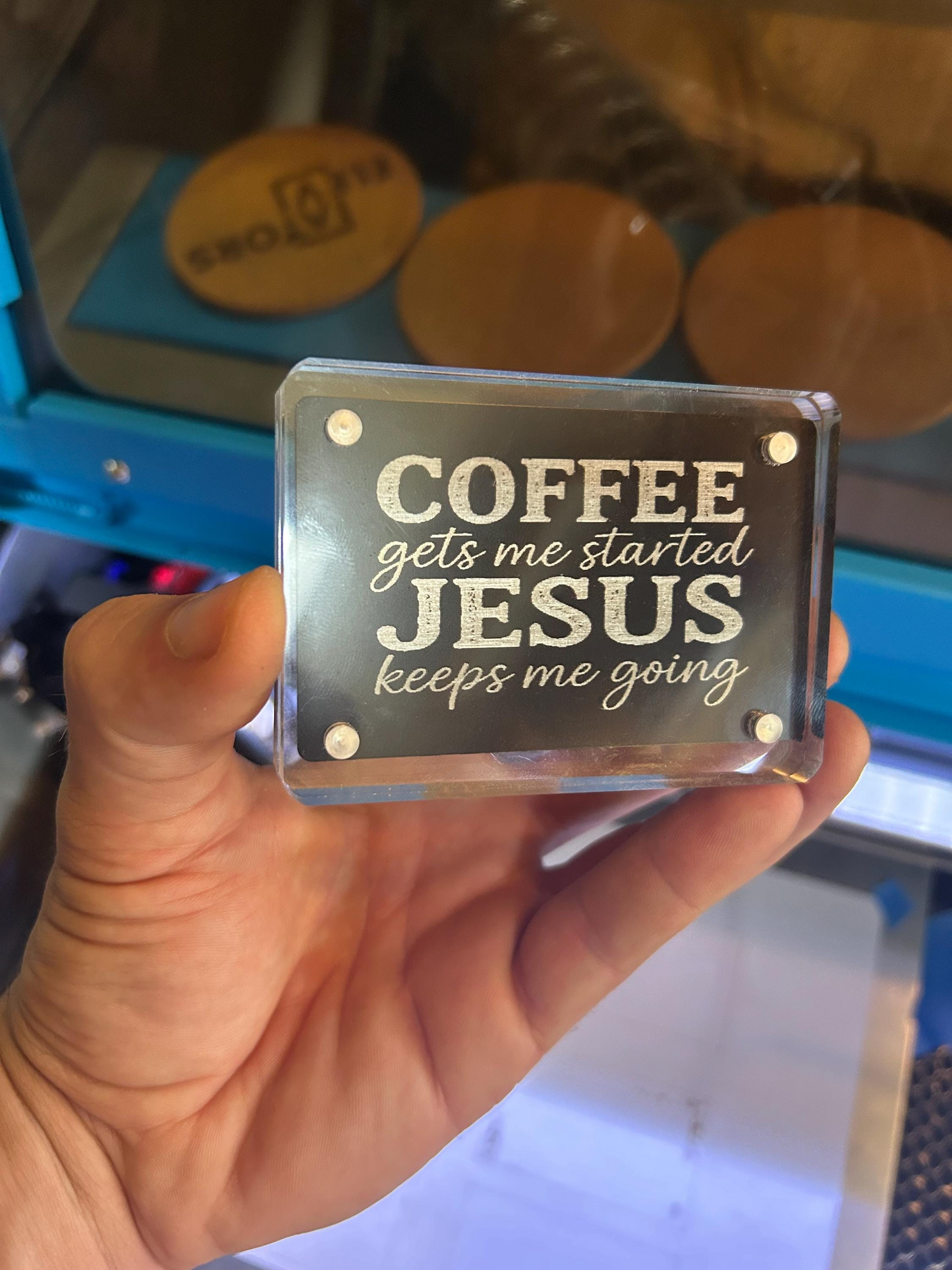 Hand presenting a religious novelty metal keepsake card in black/silver engraved with coffee and Jesus quote in optional acrylic display case