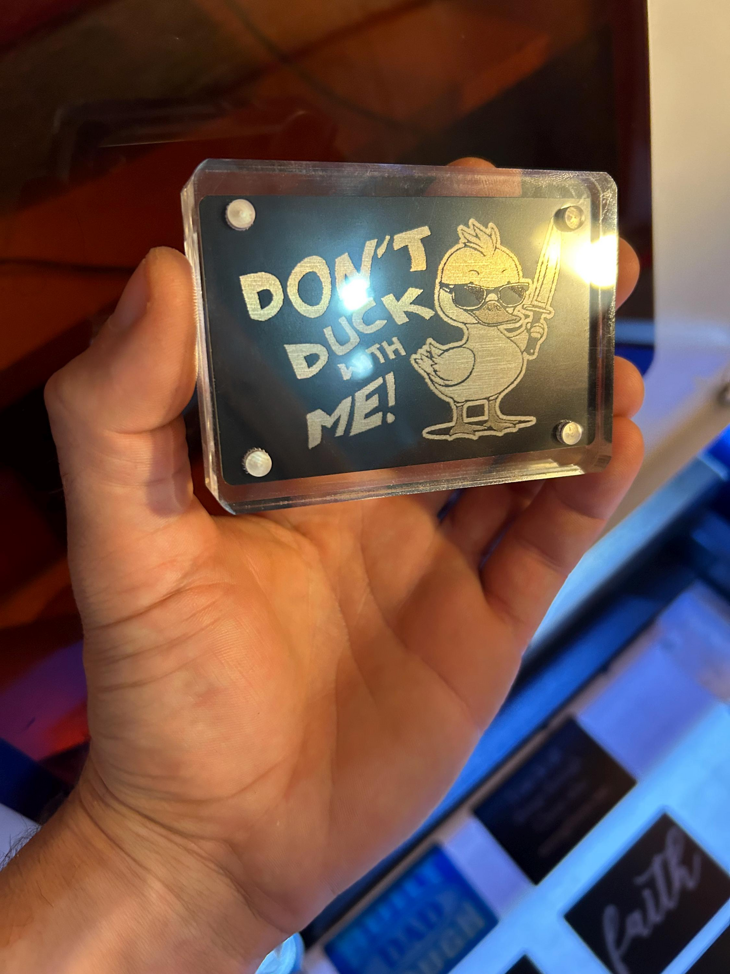 Close-up of hand displaying engraved novelty metal keepsake card featuring duckling design with “DON’T DUCK WITH ME” engraving