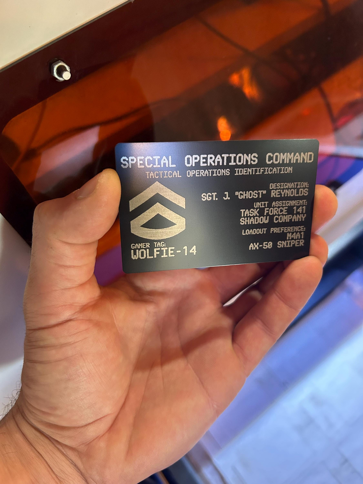 Hand holding a metal keepsake gaming gift card tactical identification badge with a blurred background