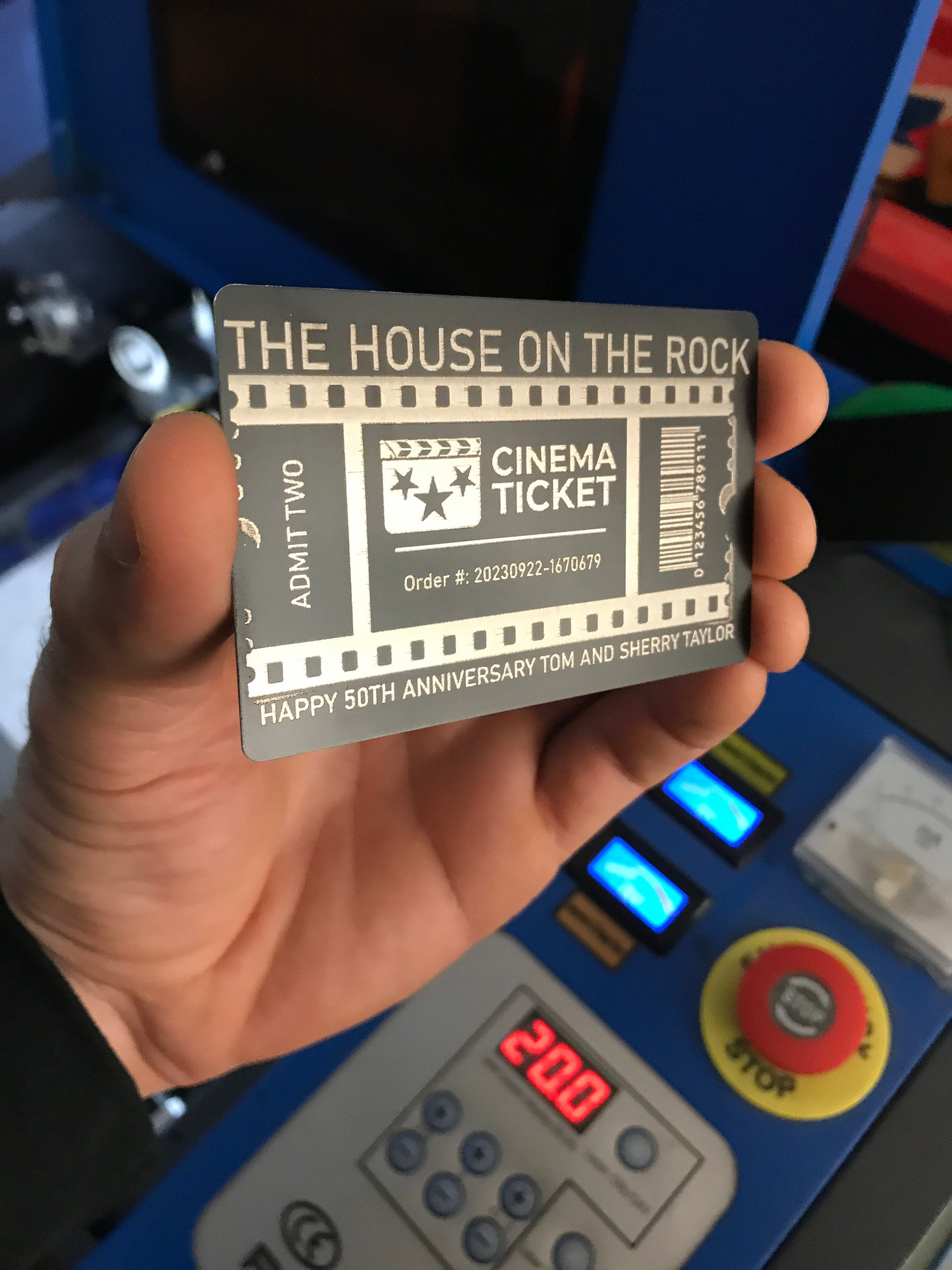 Hand holding a cinema ticket with 'custom theater logo' design against a blue machine background.
