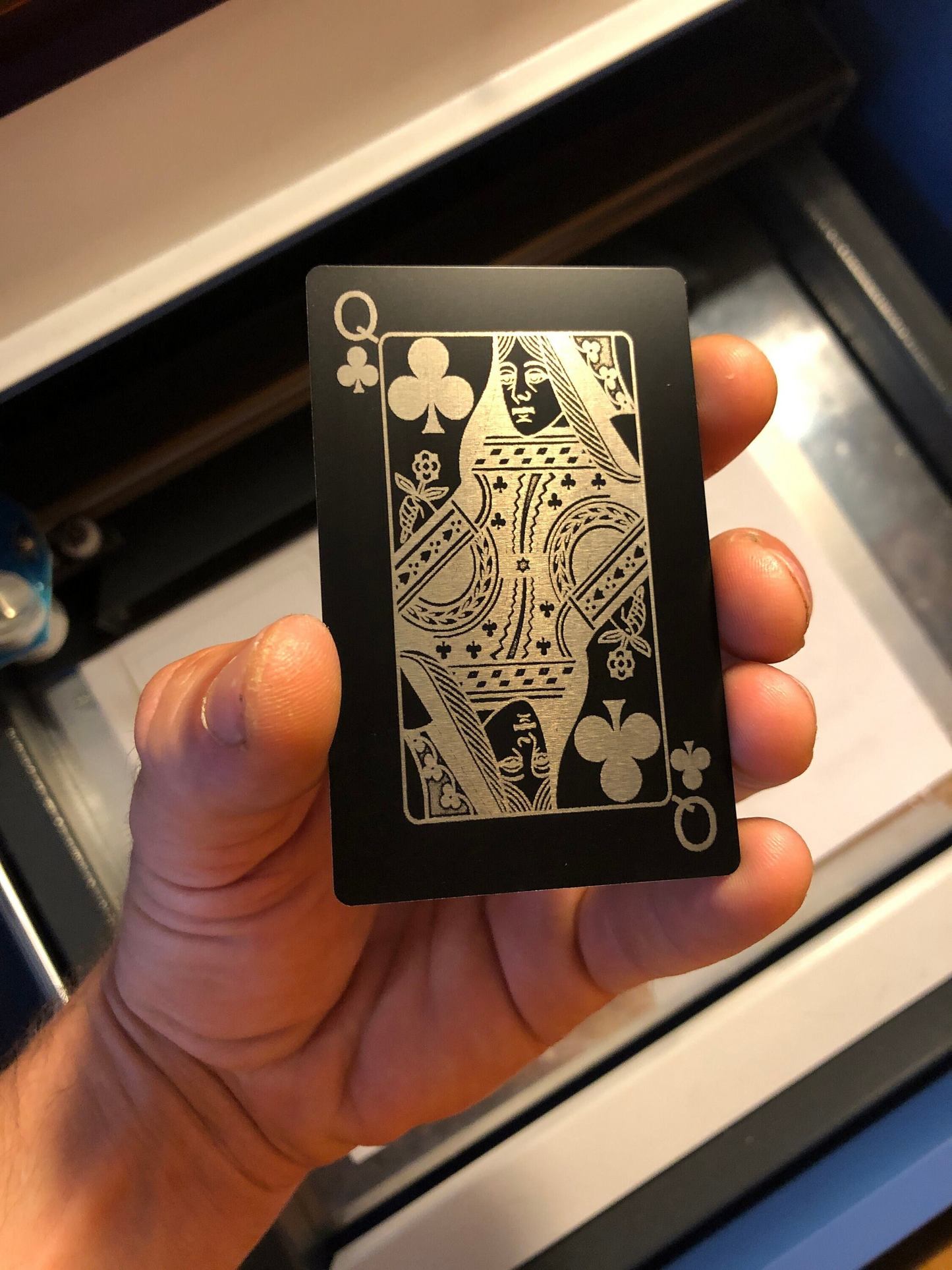 Hand holding a black metal playing card with silver design