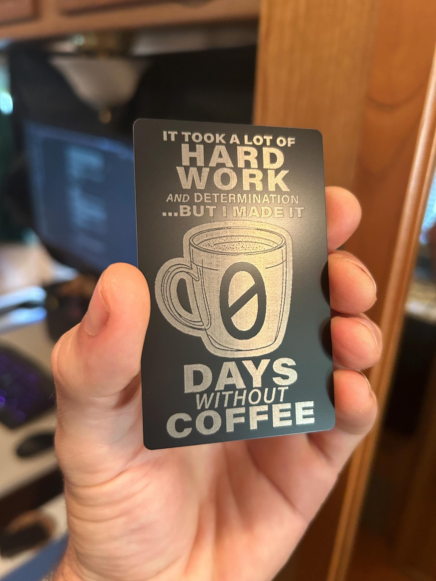 Hand holding a metal business card card with it took a lot of hard work and determination but i made it 0 days without coffee-themed text and design