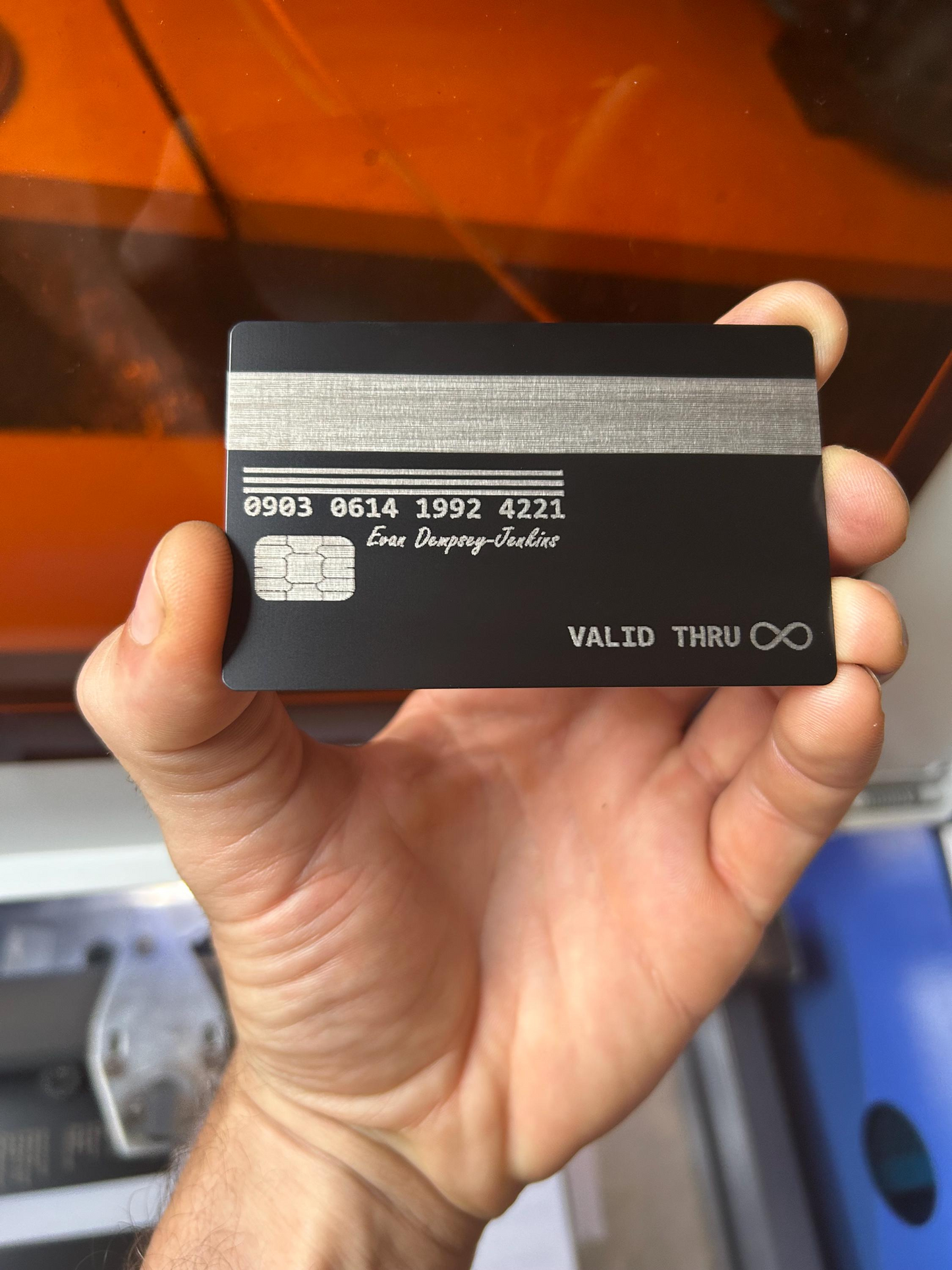 Hand holding a black card with text against an orange background