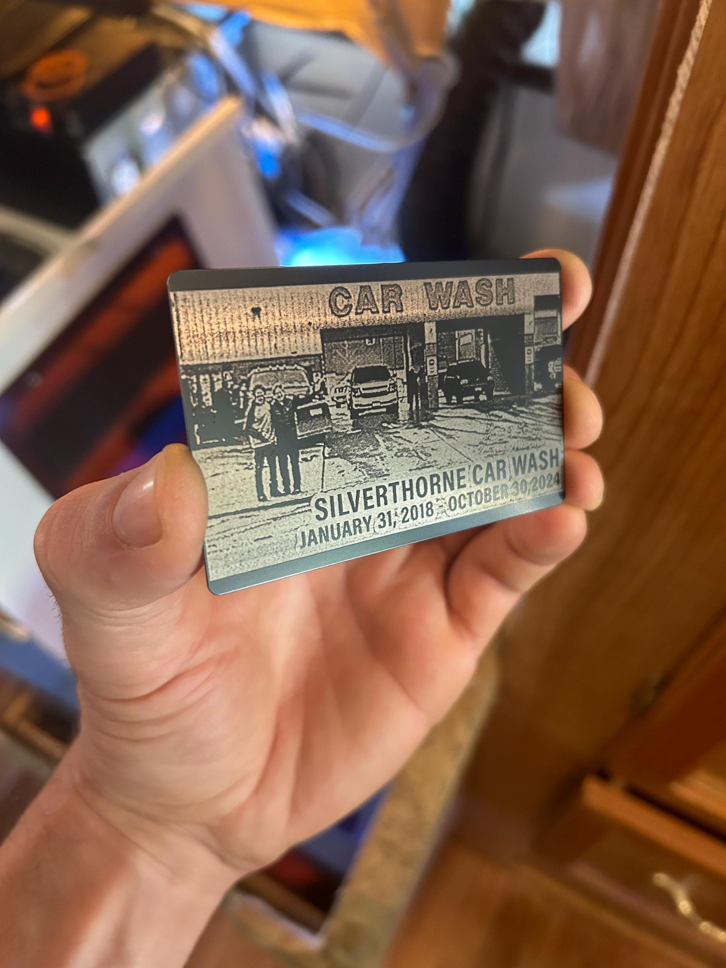 Hand holding a metal photo engraving card with 'Car Wash Silverthorne' business design