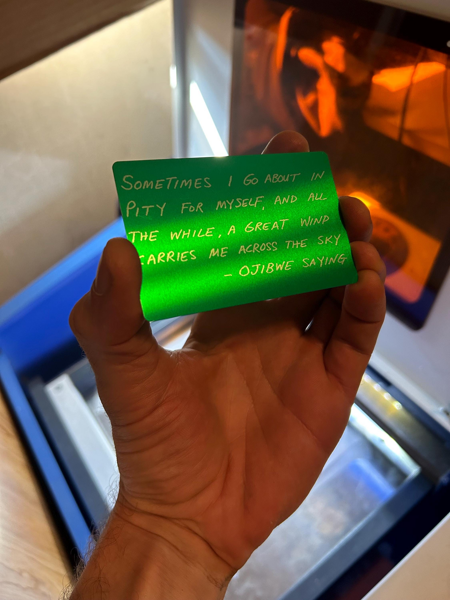 Hand holding a green card with text in front of a blurred background