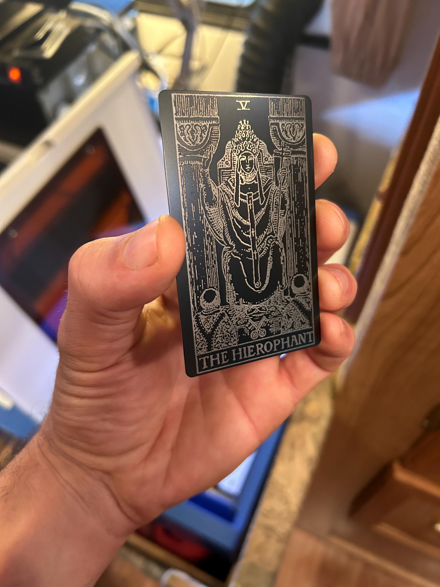 Hand holding a black tarot card with intricate design and text.