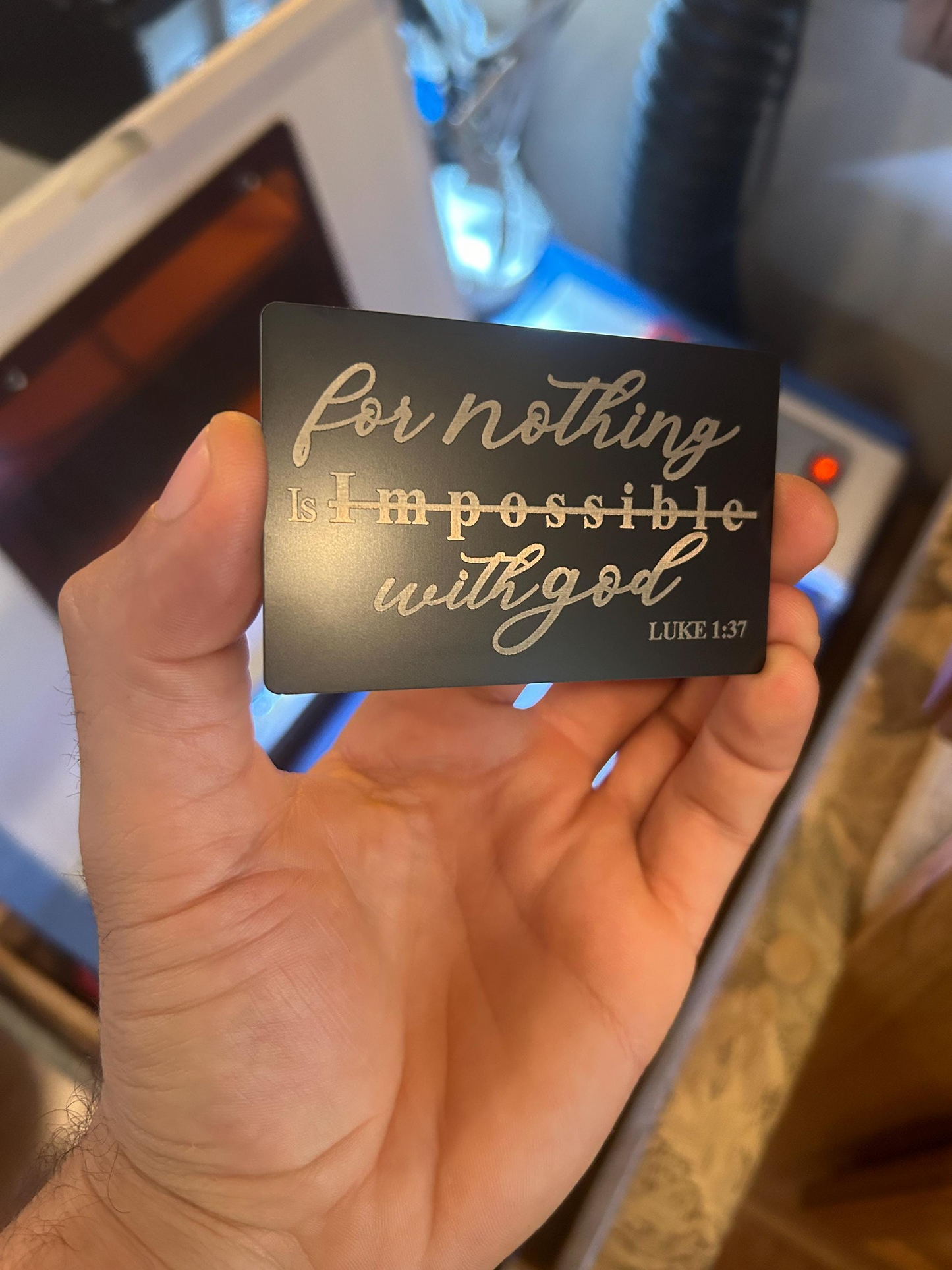 Hand holding a card with 'For nothing is impossible with God' quote, blurred background