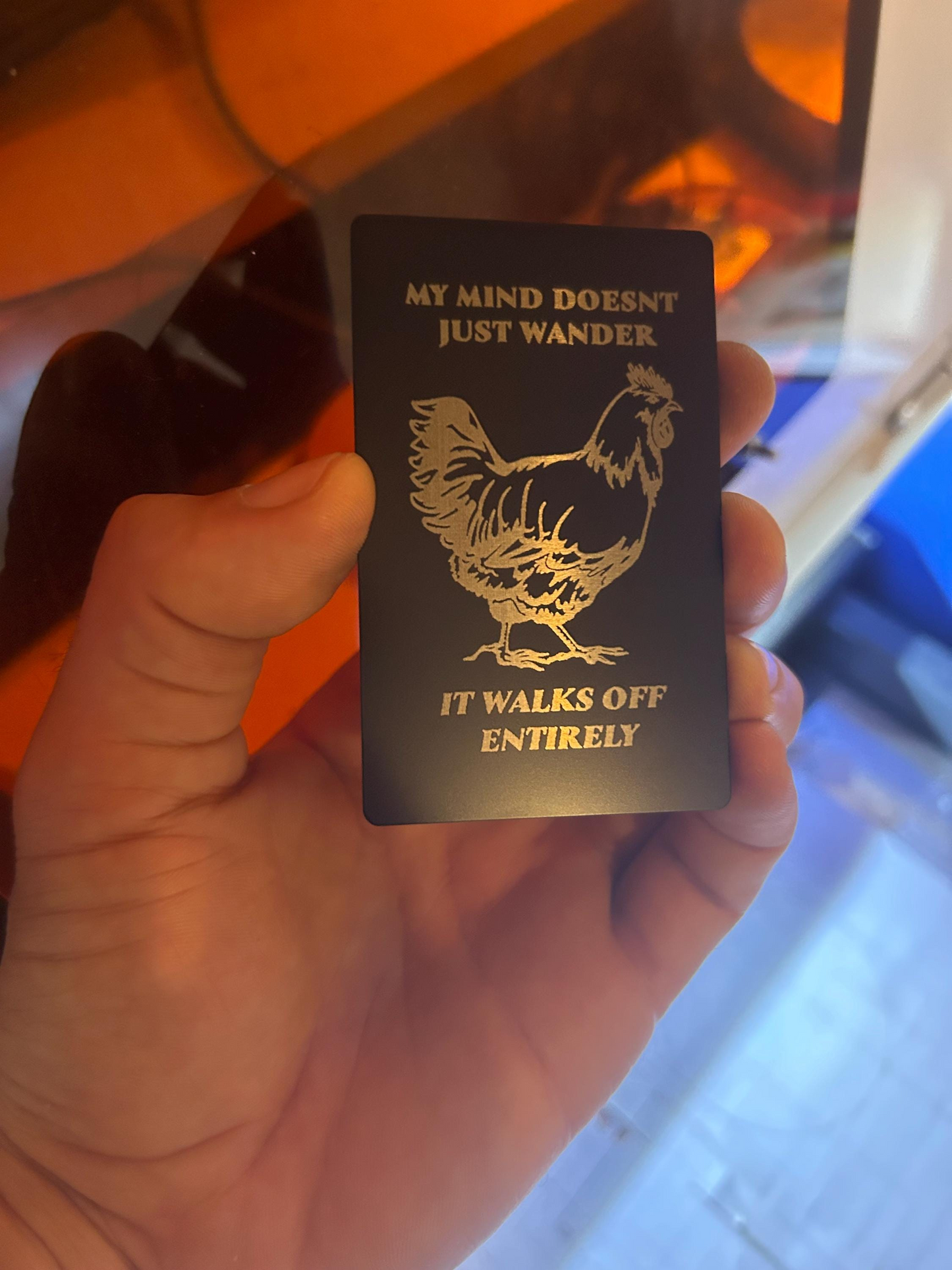 Close-up of engraved anodized aluminum novelty card featuring funny chicken artwork with wandering mind quote