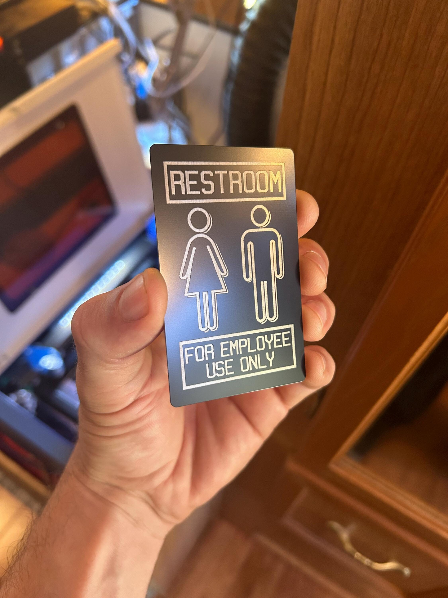 Hand holding a restroom sign for employee use only in front of a machine