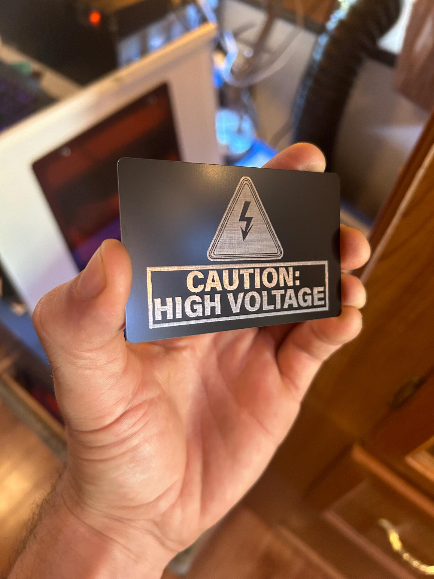 Hand holding a card with a high voltage warning sign.