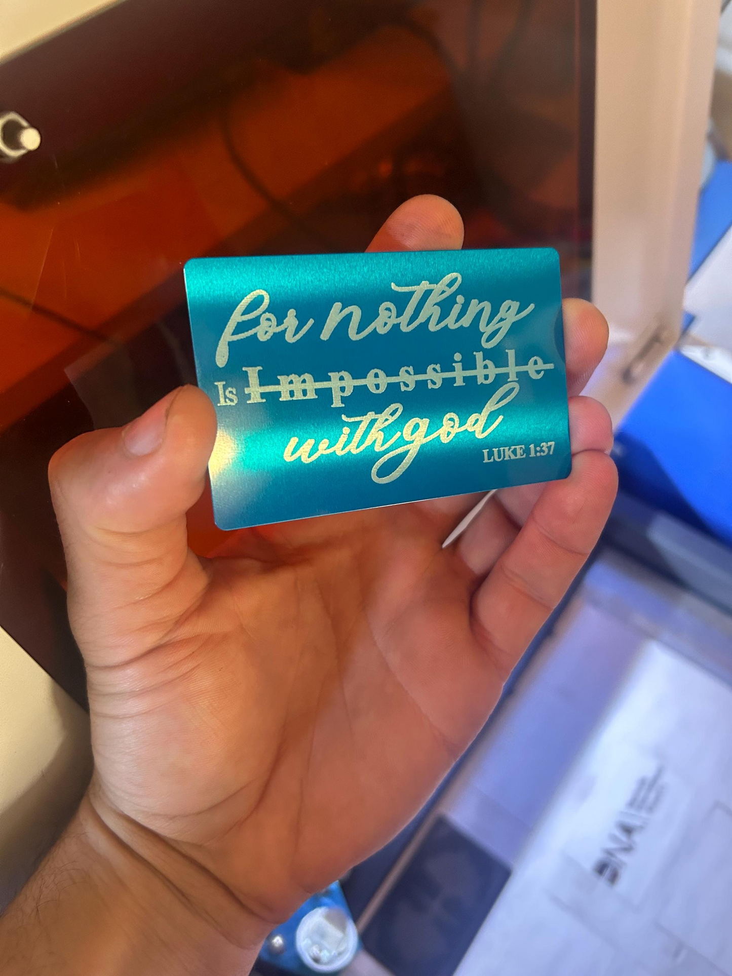 Hand holding a blue card with motivational quote in front of a blurred background