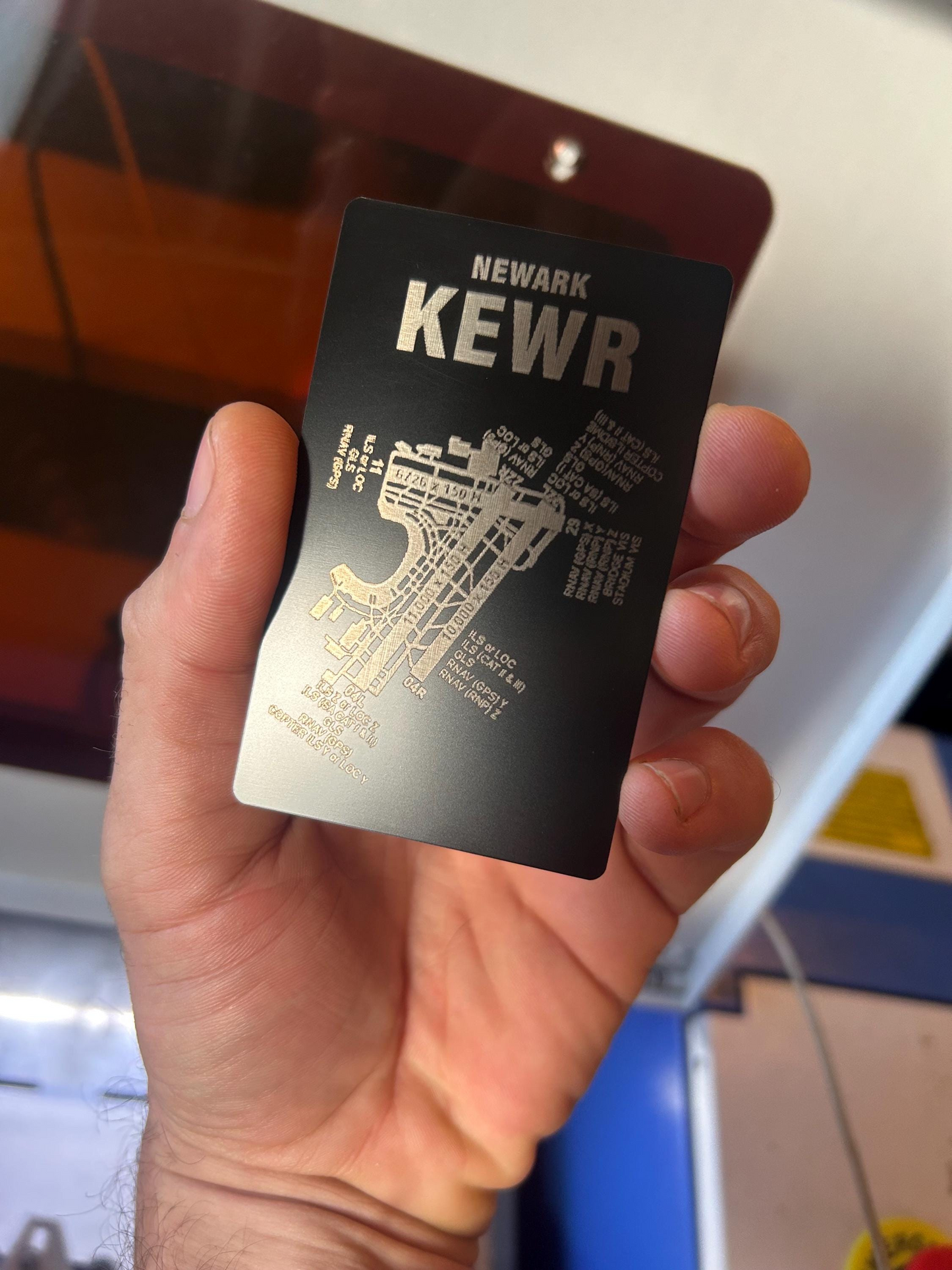 Hand holding a metallic card with airport diagram text and map design.