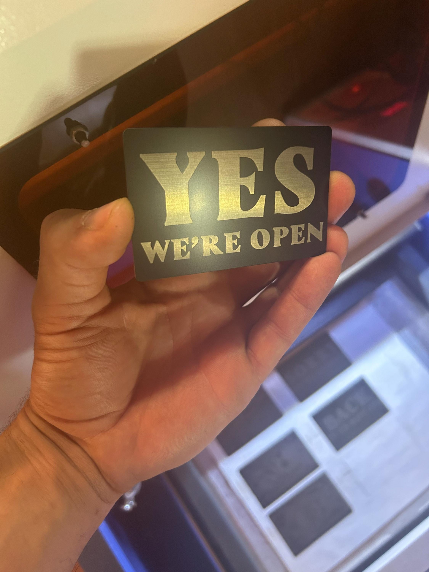Hand holding a sign that reads 'YES WE'RE OPEN'