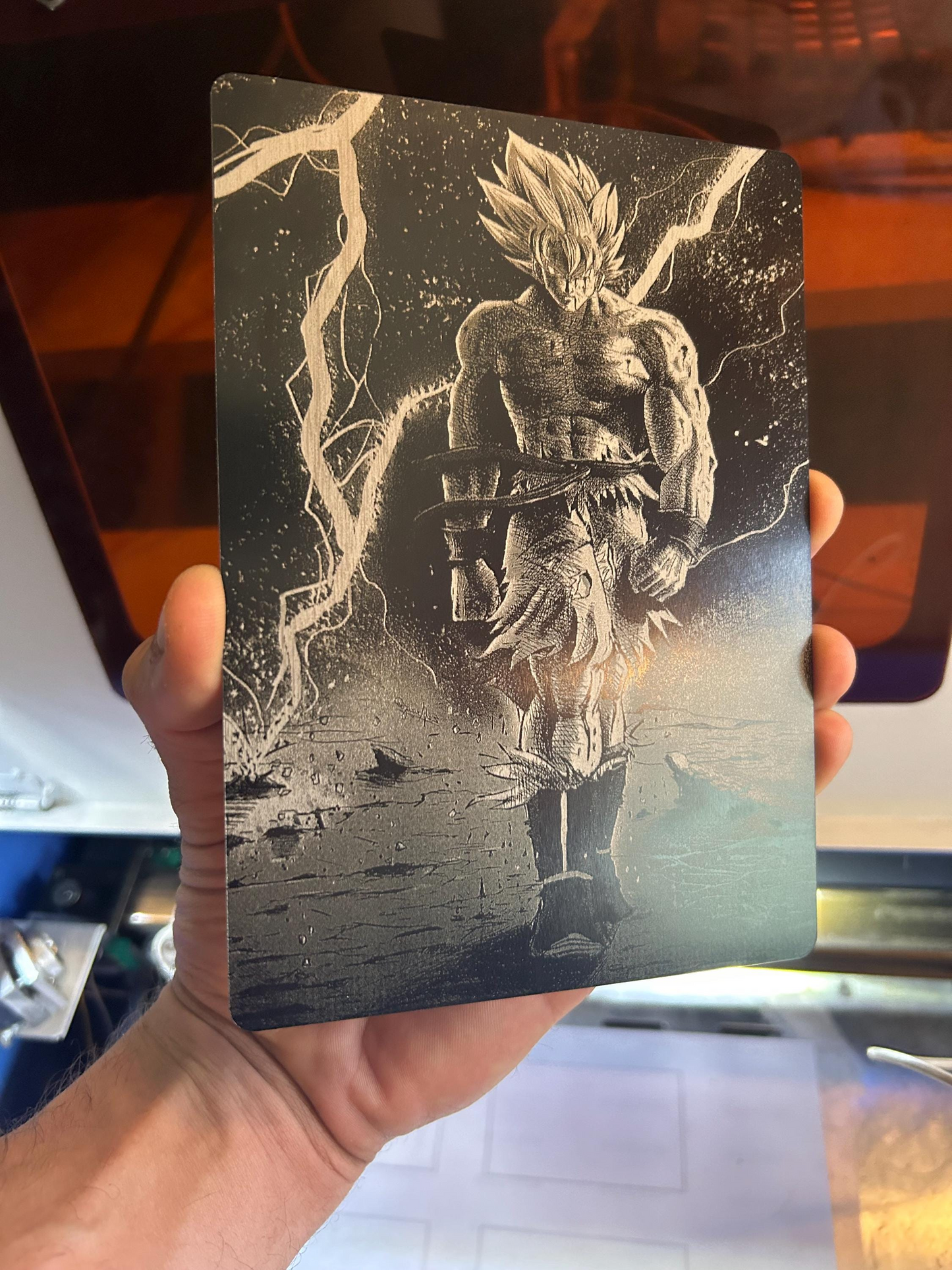 Hand holding a laser engraved manga line art illustration of a warrior design against a blurred background