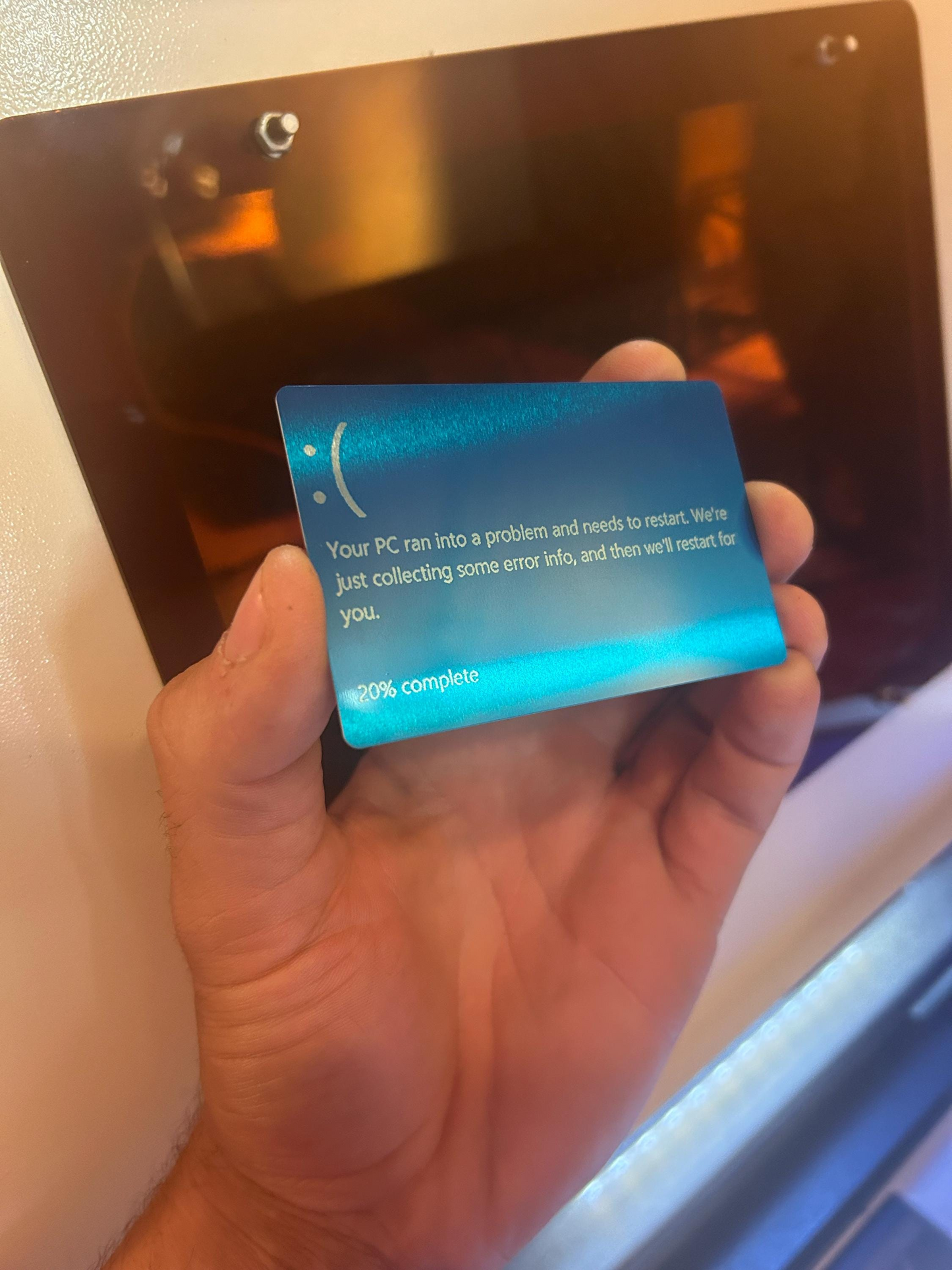 Hand holding a blue error card in front of a computer screen