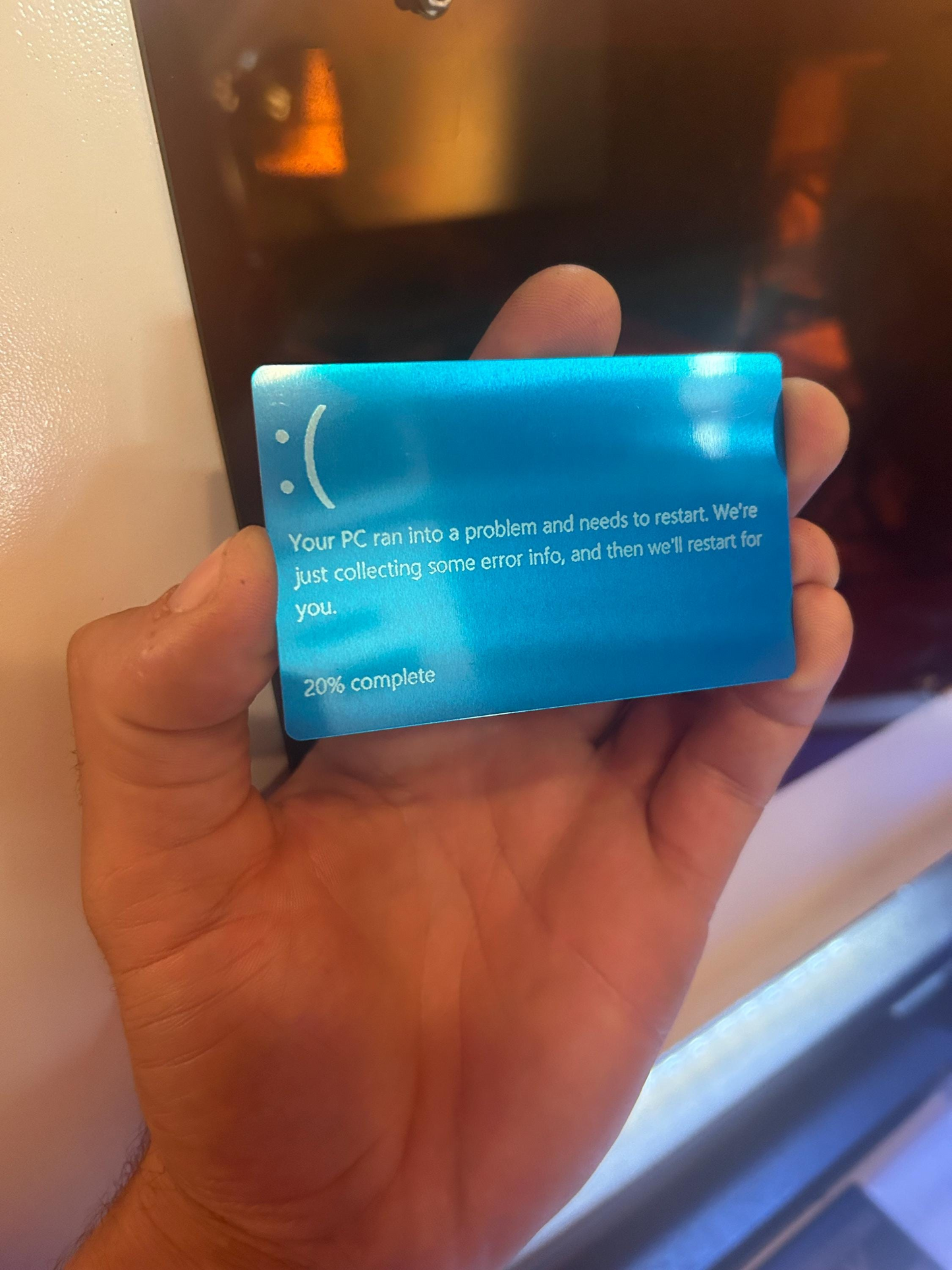 Hand holding a blue/silver metal error card with text on a blurred background