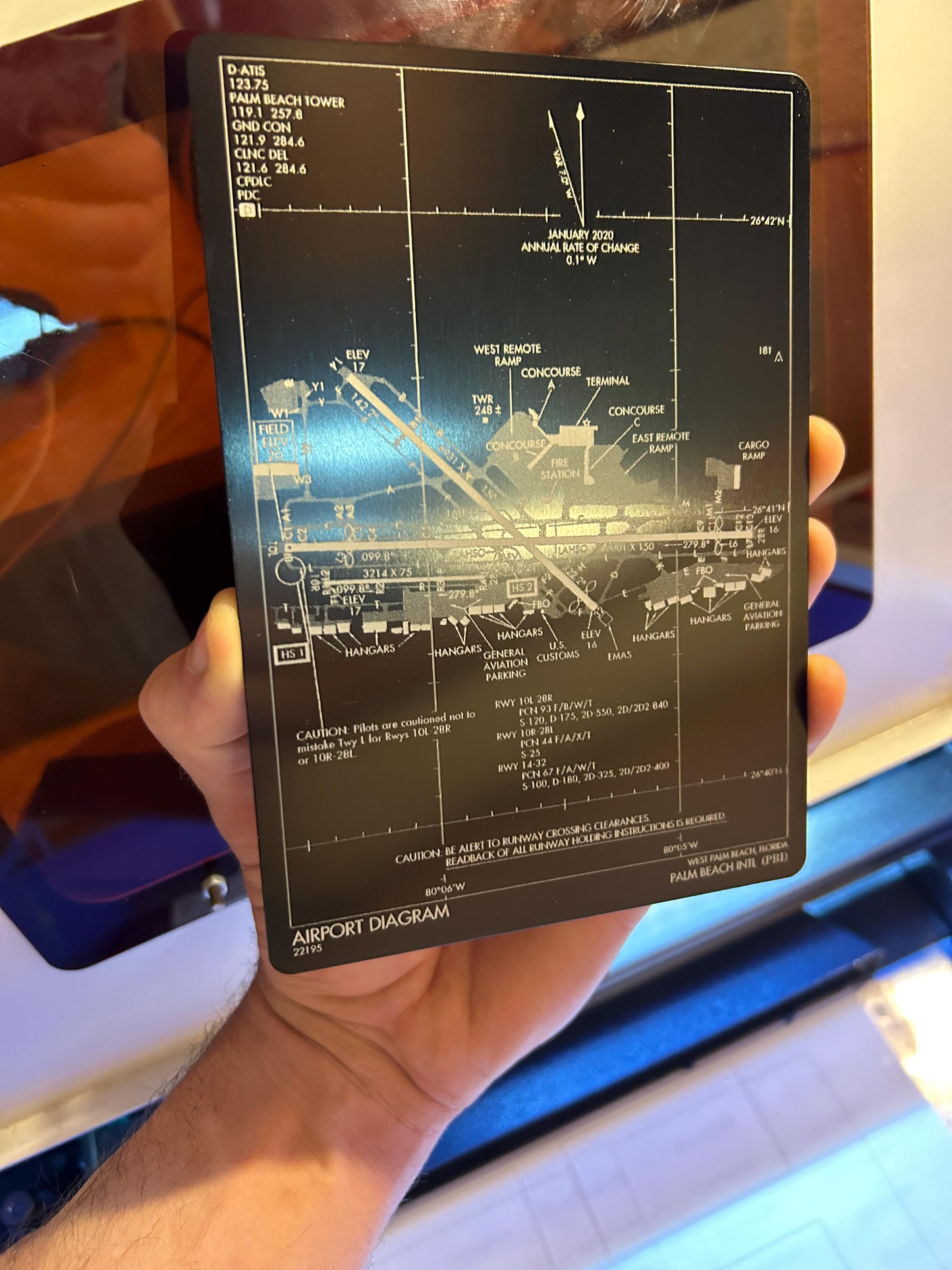Hand holding a black 5x7 plaque with an airport diagram