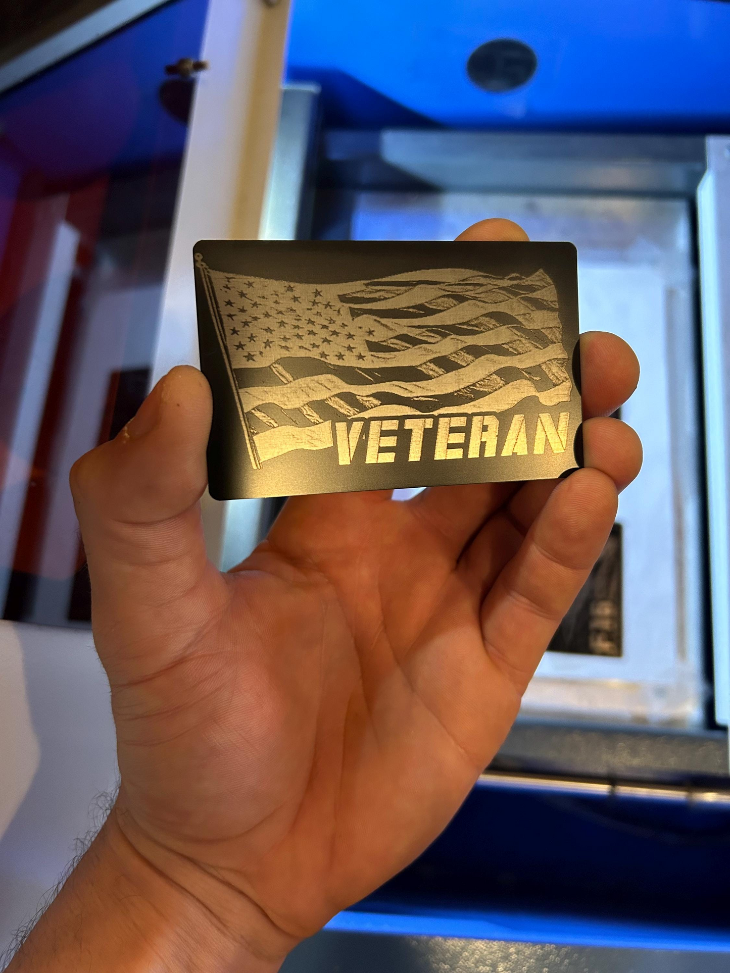 Hand holding a metal keepsake card with 'VETERAN' and an American flag design.