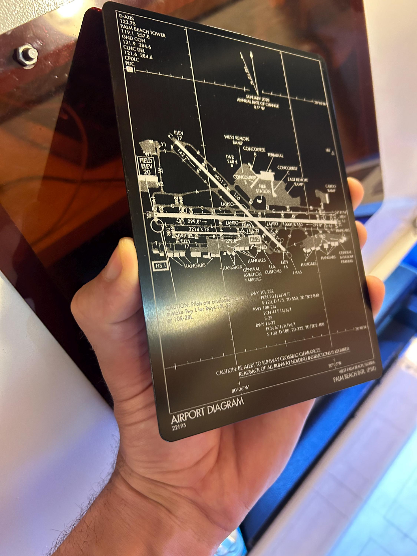 Hand holding a black and silver laser engraved airport approach plate engraving