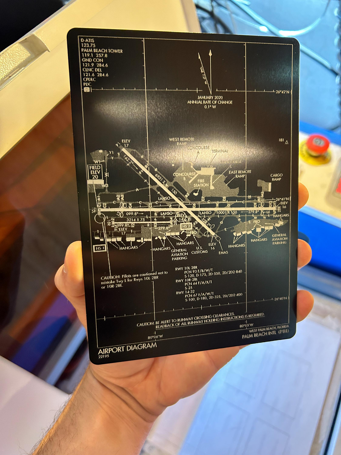 Hand holding a metal 5x7" plaque in black/silver with airport diagram laser engraved