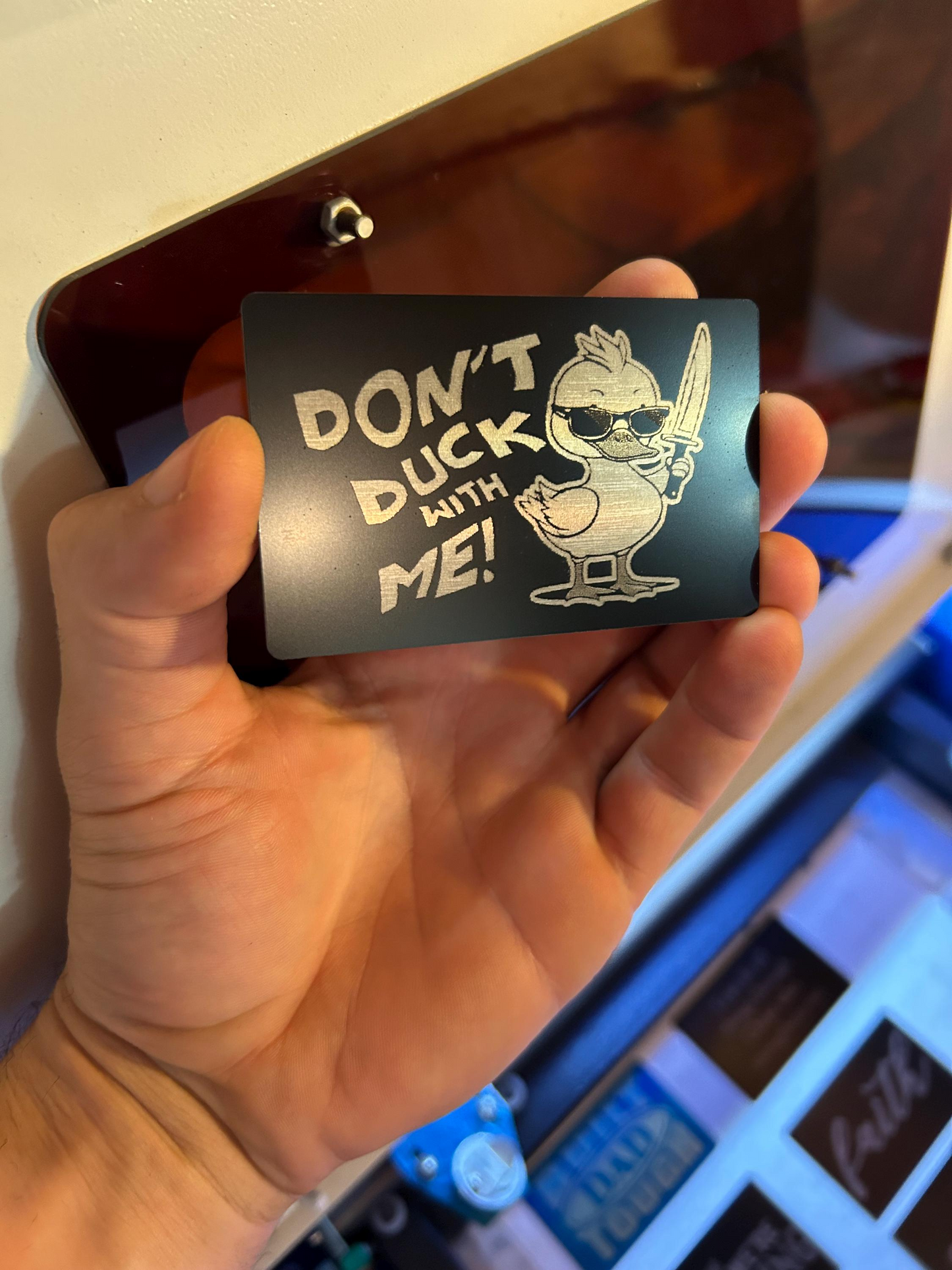 Hand presenting engraved black and silver gag gift card with humorous duckling and “DON’T DUCK WITH ME” message
