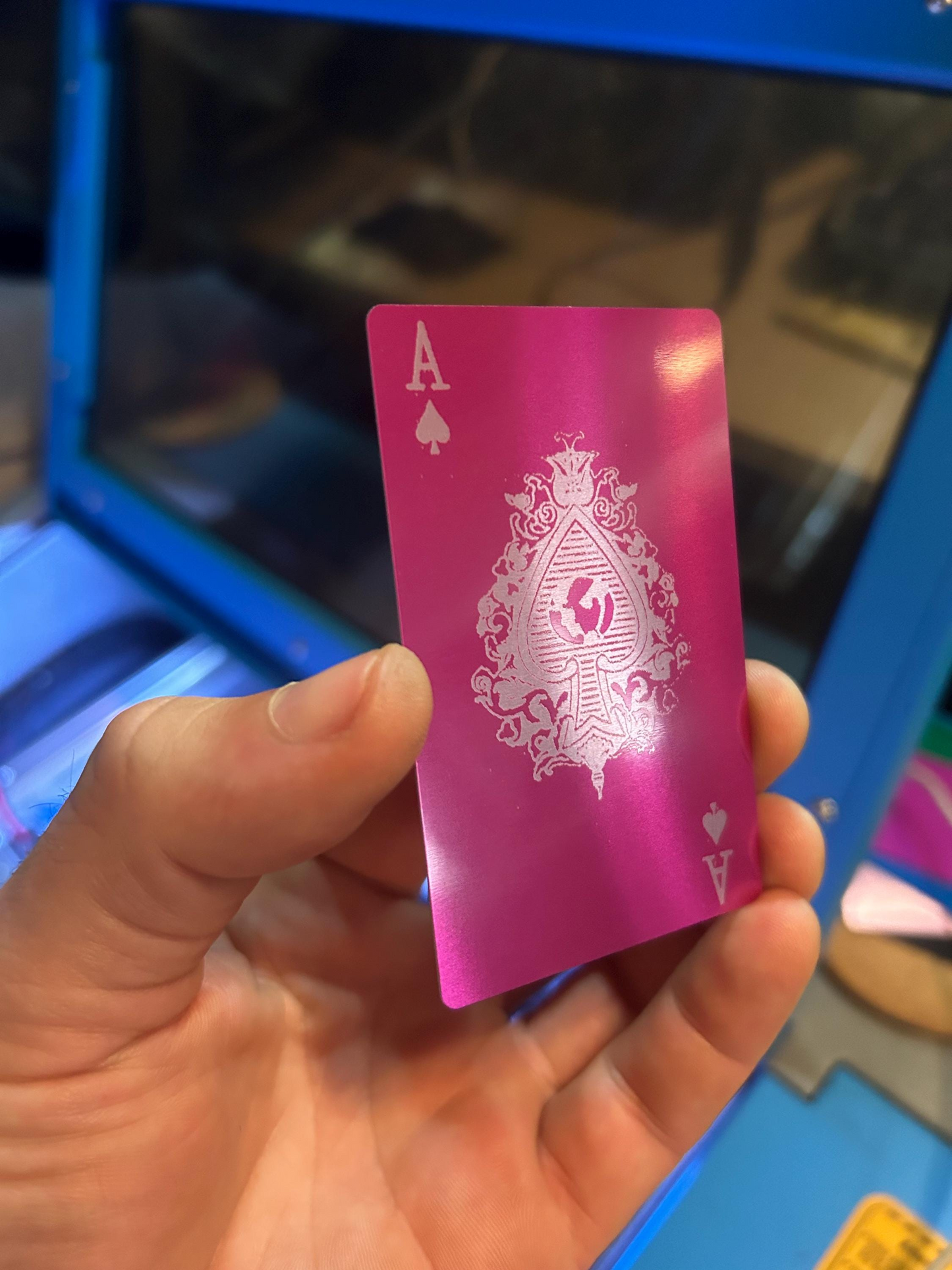 Purple/silver metal ace of spades poker card, in front of a laser cnc machine