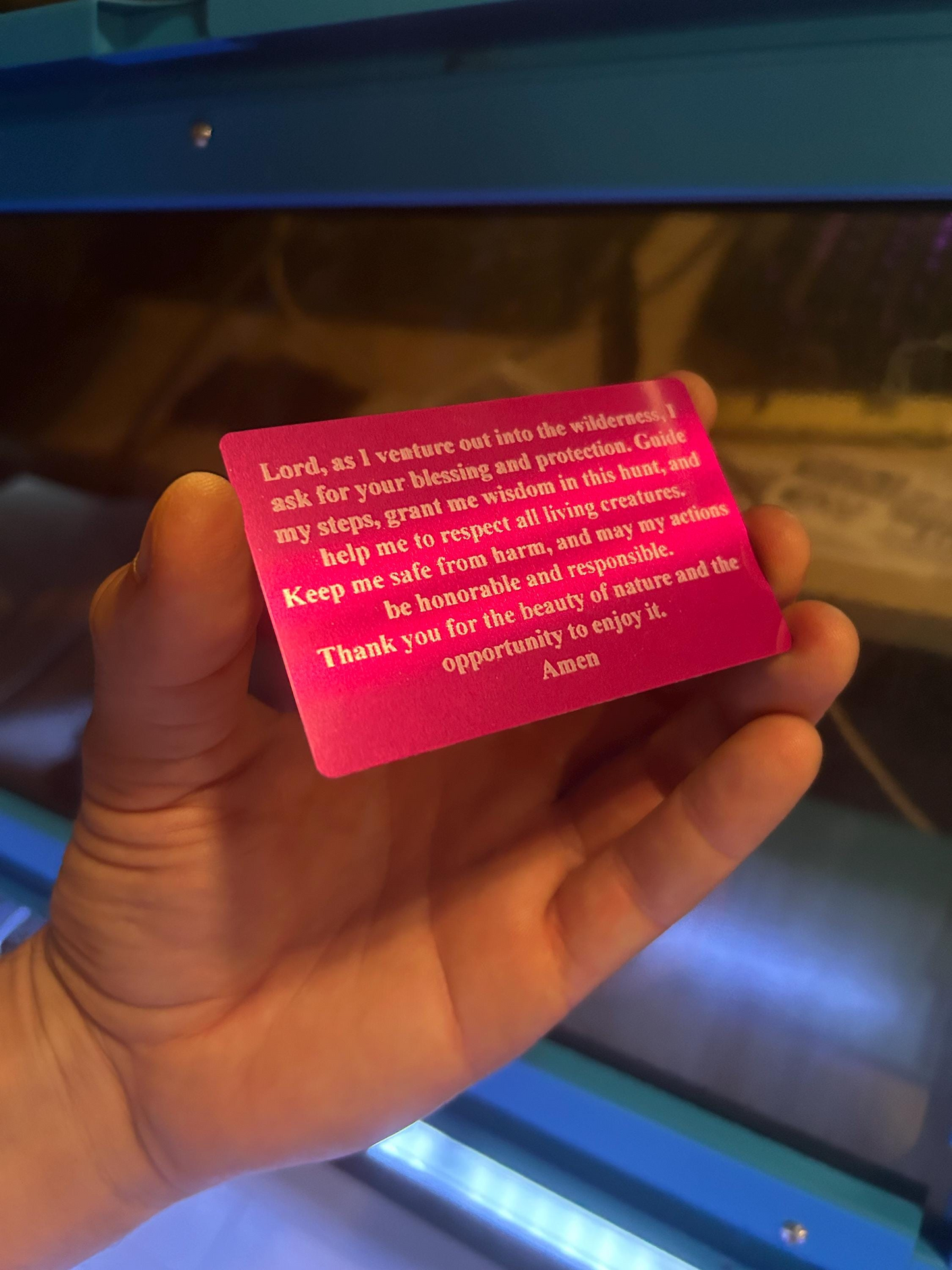 Hand holding a purple and silver metal laser engraved prayer card with personalized text.