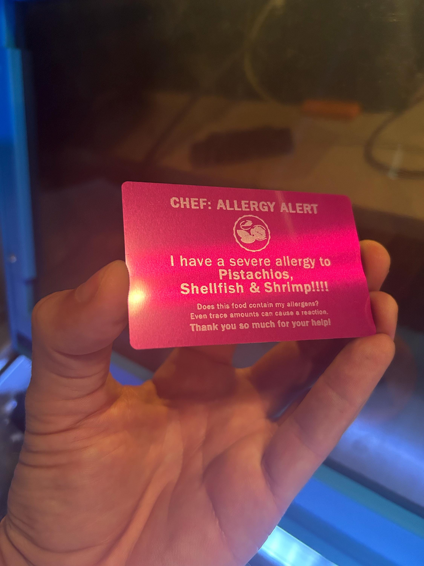 Hand holding a purple metal food allergy alert card with customized text