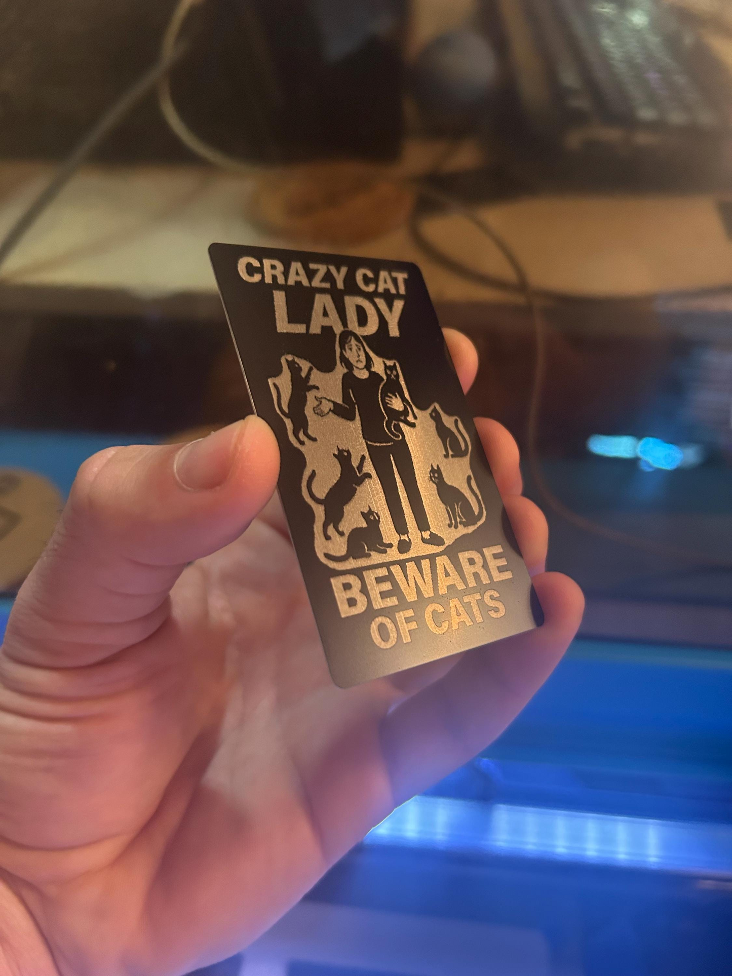 Close-up of engraved anodized aluminum cat lover card featuring silly “CRAZY CAT LADY” phrase and kitten illustrations