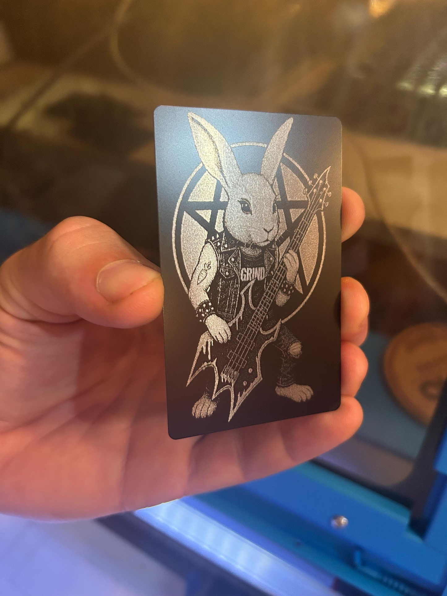 Hand holding an anodized aluminum musician gift card with a rocker rabbit playing a guitar design