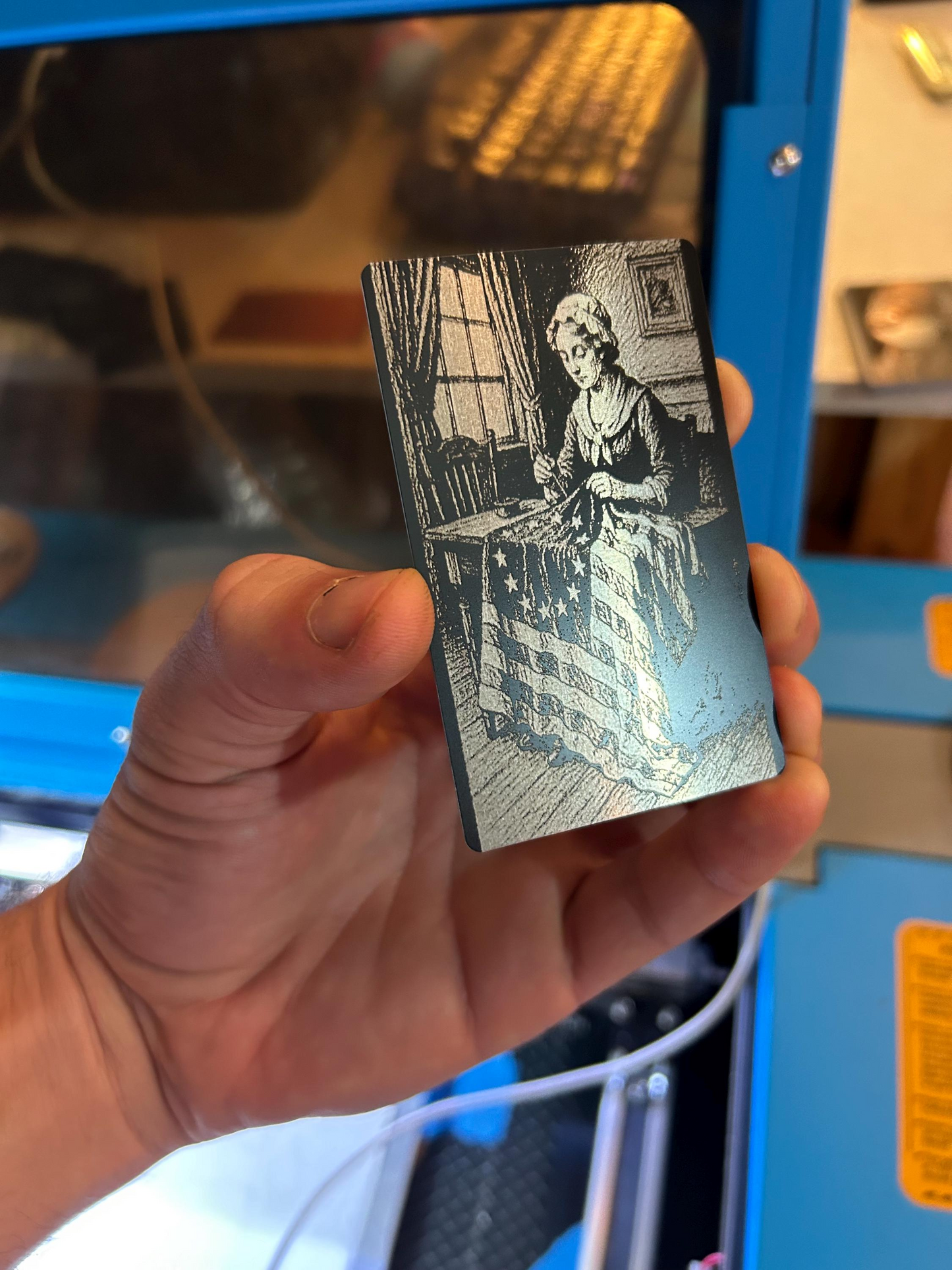 Hand holding a small engraved card with a patriotic design.