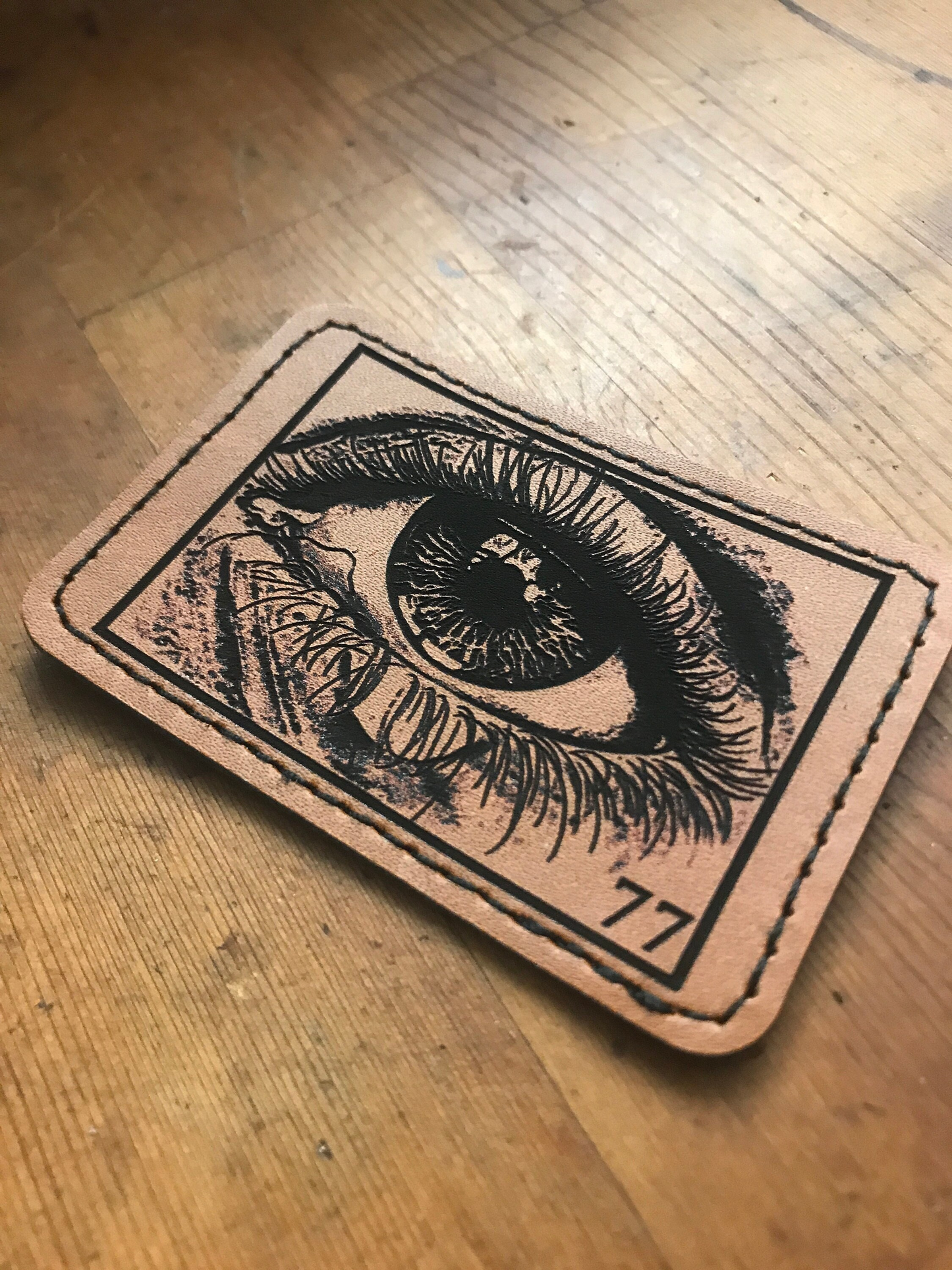 Leather eye ball patch with laser engraved highly detailed surreal illustration and angel 77 numbers