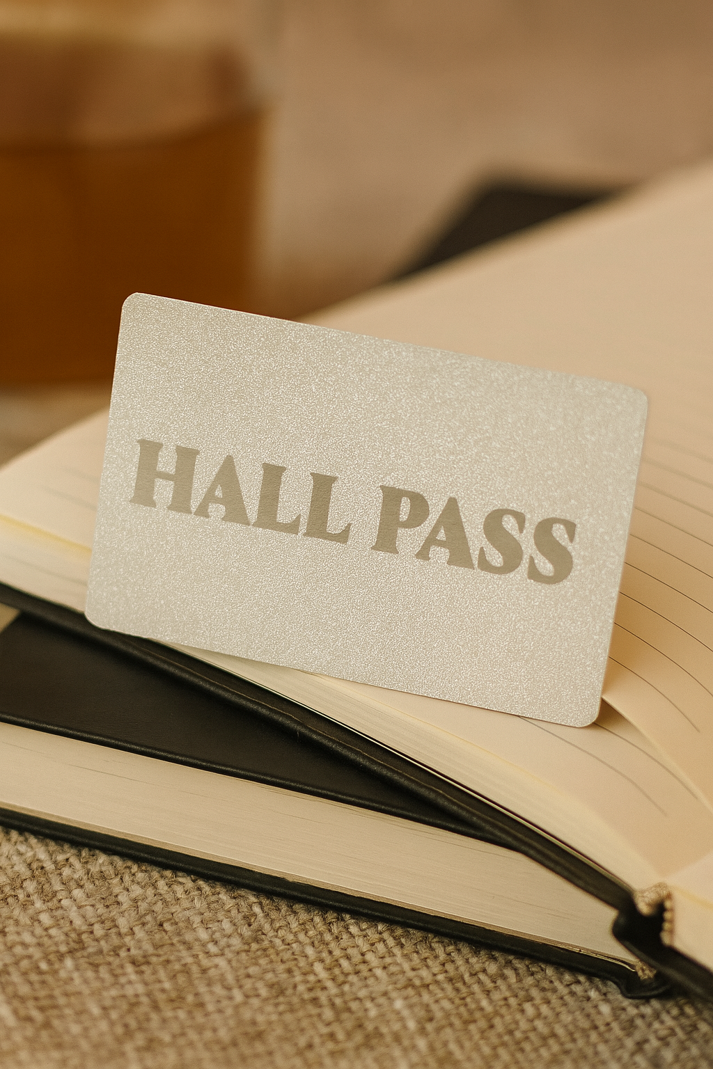 Hall pass metal card on top of an open book with a textured background