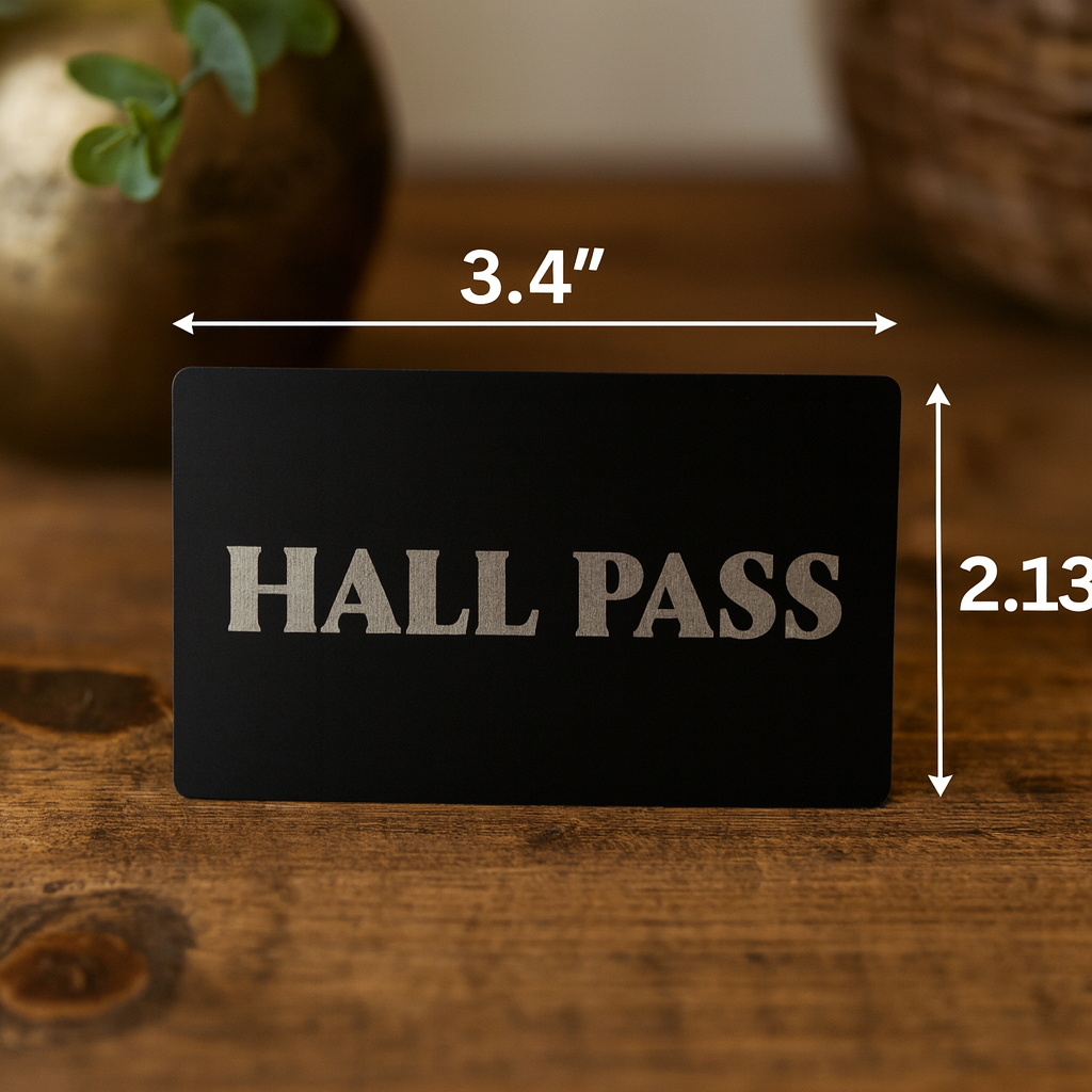 Anodized aluminum black/silver 'HALL PASS' card with measurements on a wooden surface