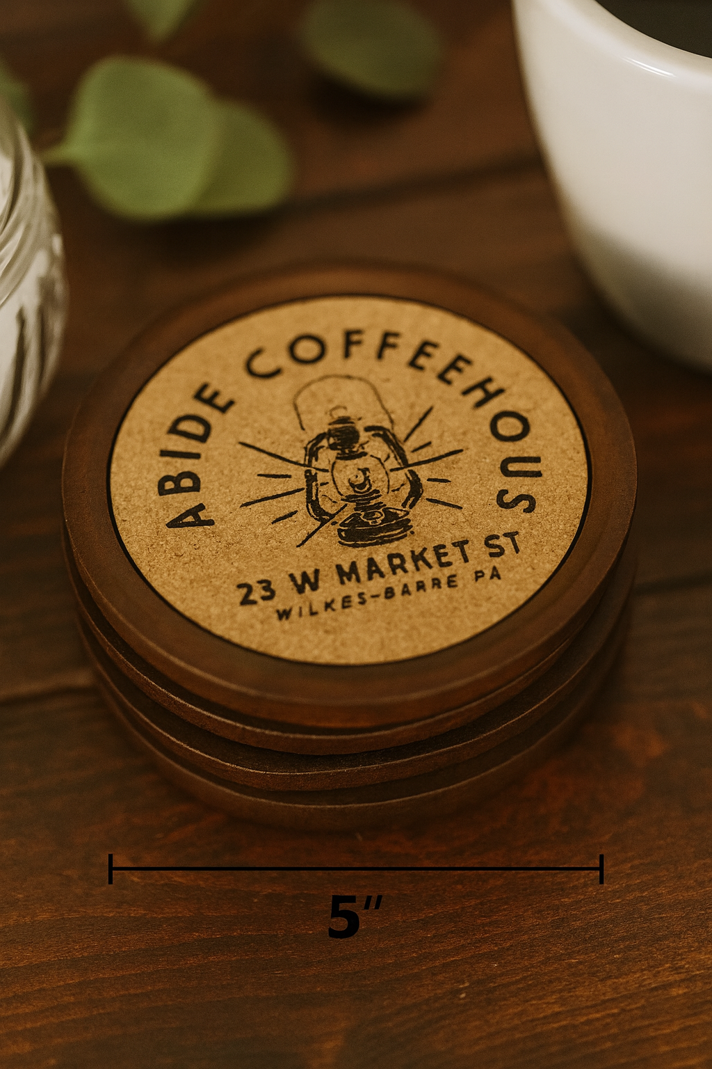Stack of cork/wood Coffeehouse coasters on a wooden surface with a cup in the background.