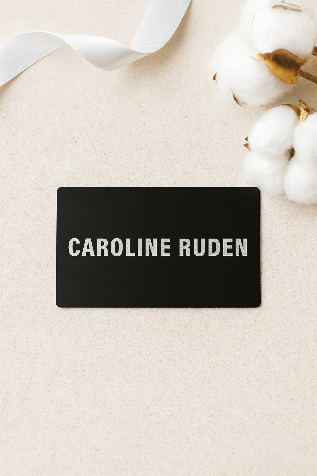 Black metal nameplate with 'personalized name engraving' on a beige background with white flowers.