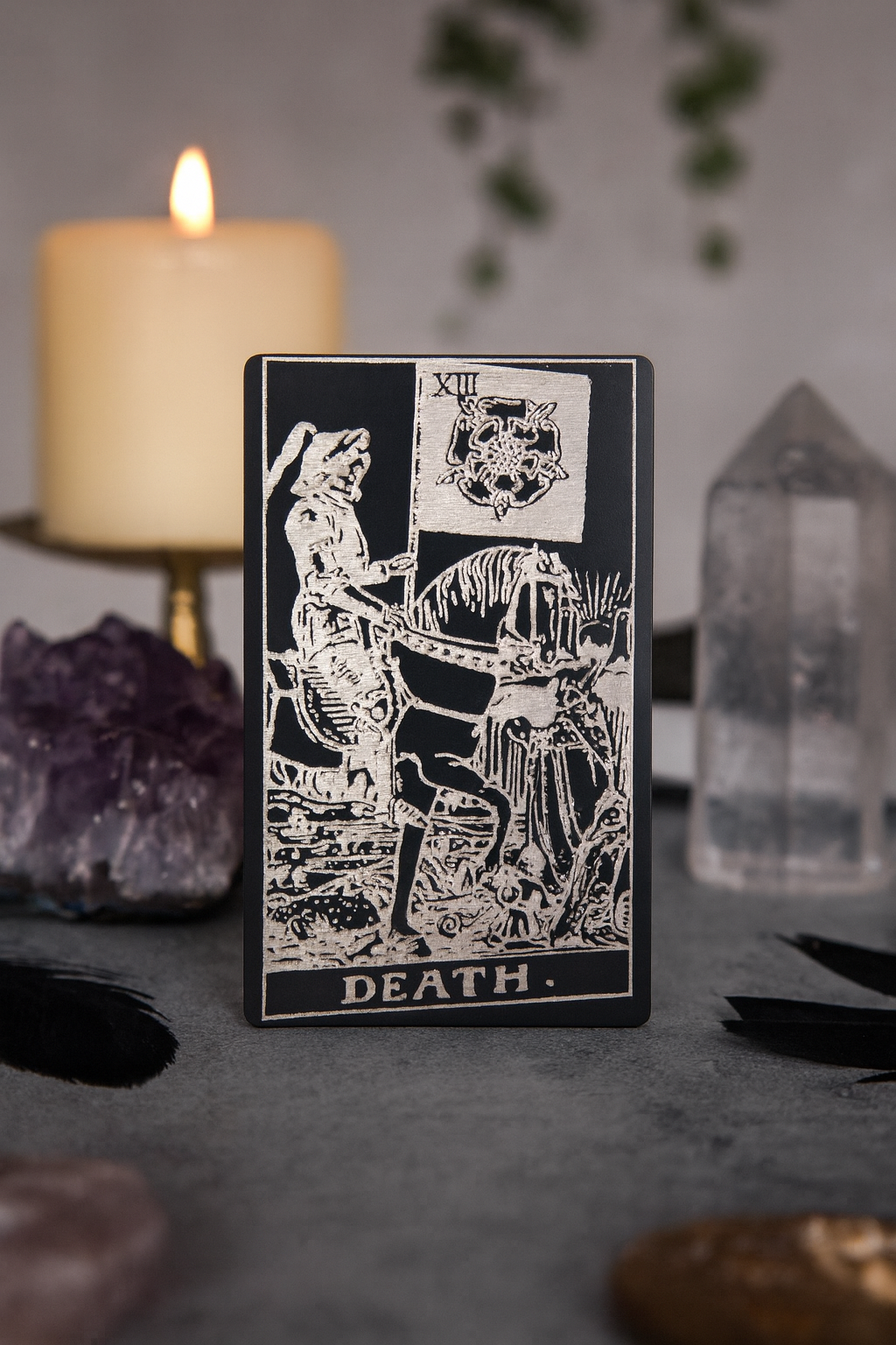 Metal black/silver Tarot card titled 'Death' with a candle and crystals in the background
