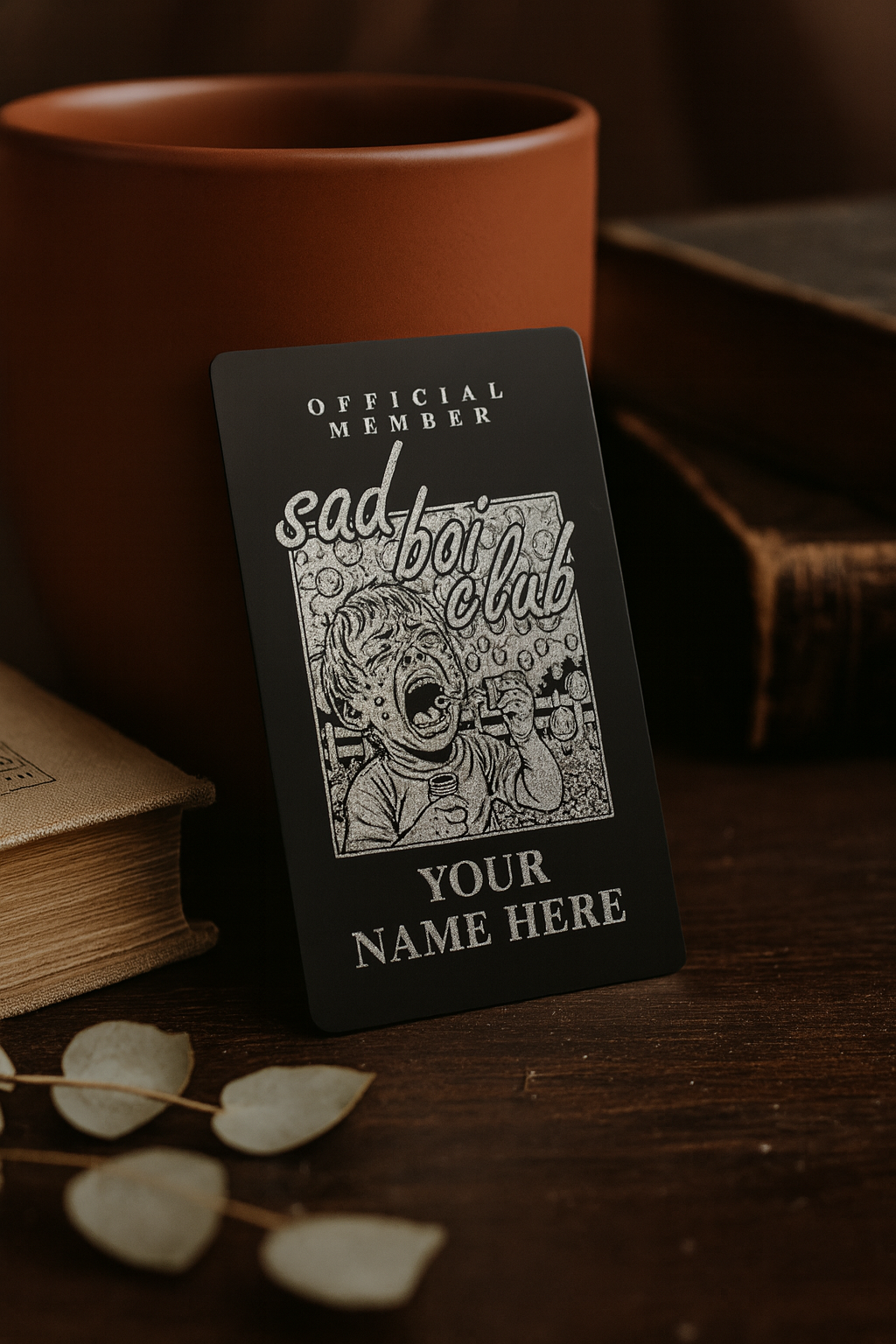 laser engraved metal card with official member sad boi club with personalized text engraving of any name on the front, photographed on a wooden table